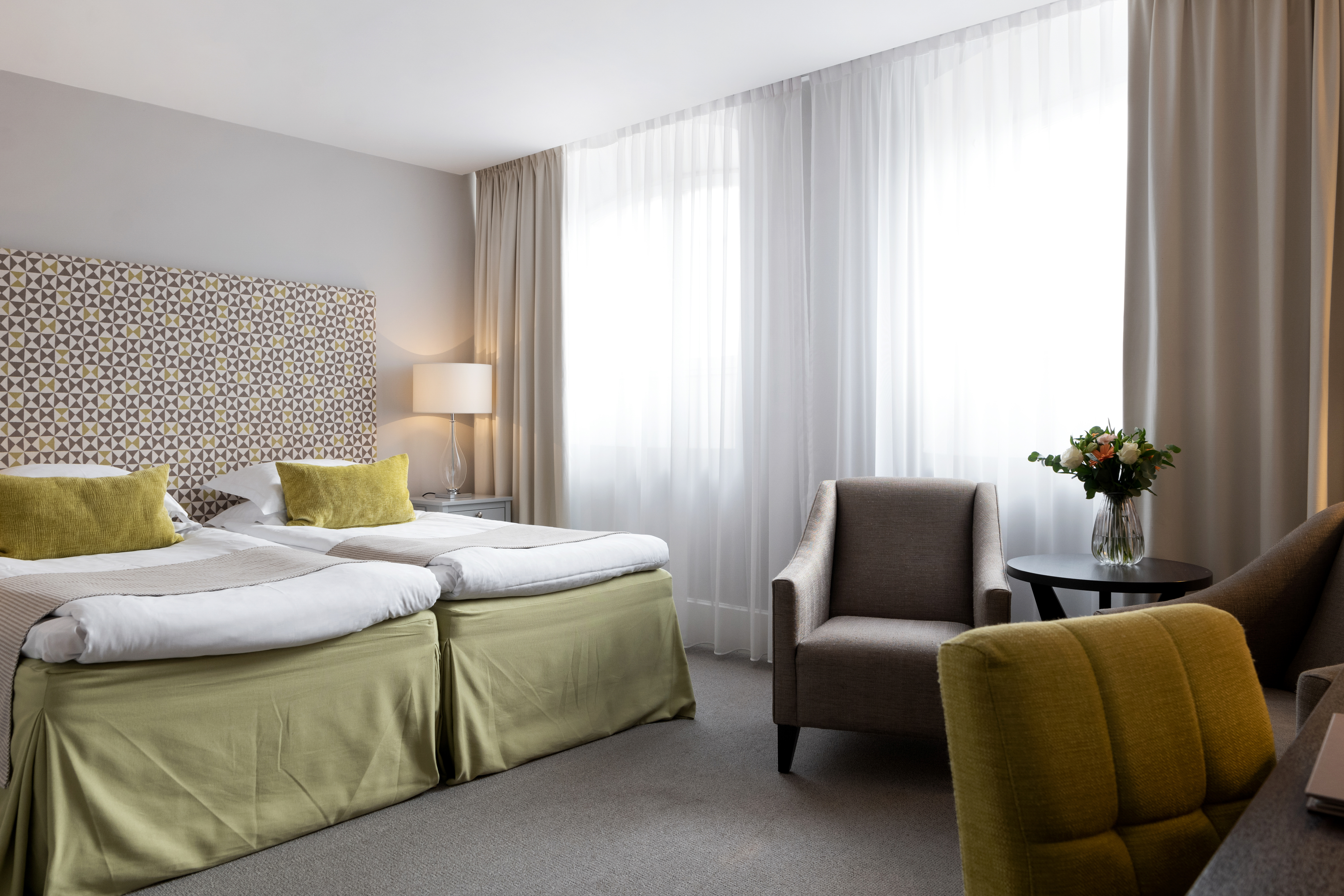 Hotel room with bed, window and armchairs