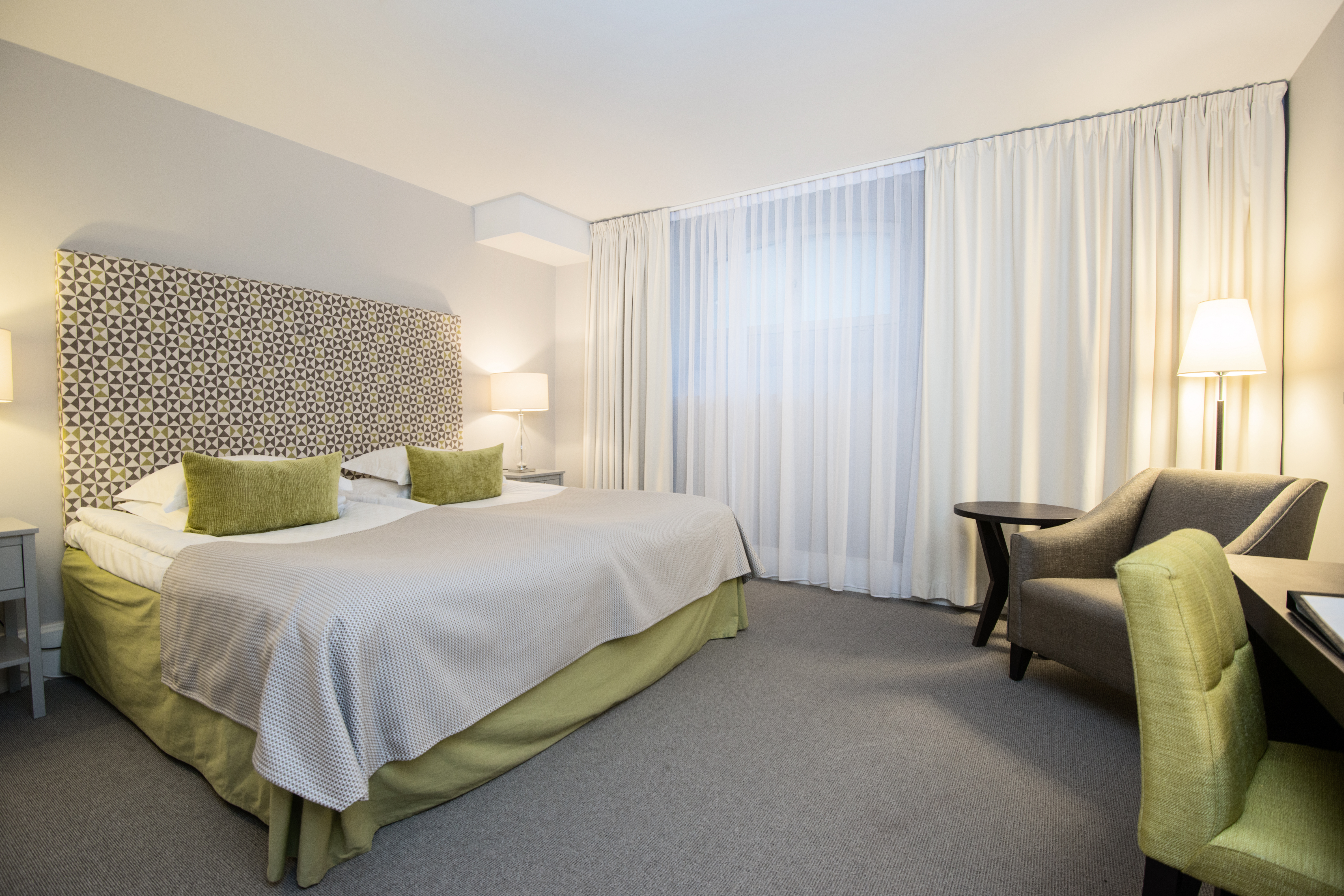 Bright hotel room with bed, armchair and curtains