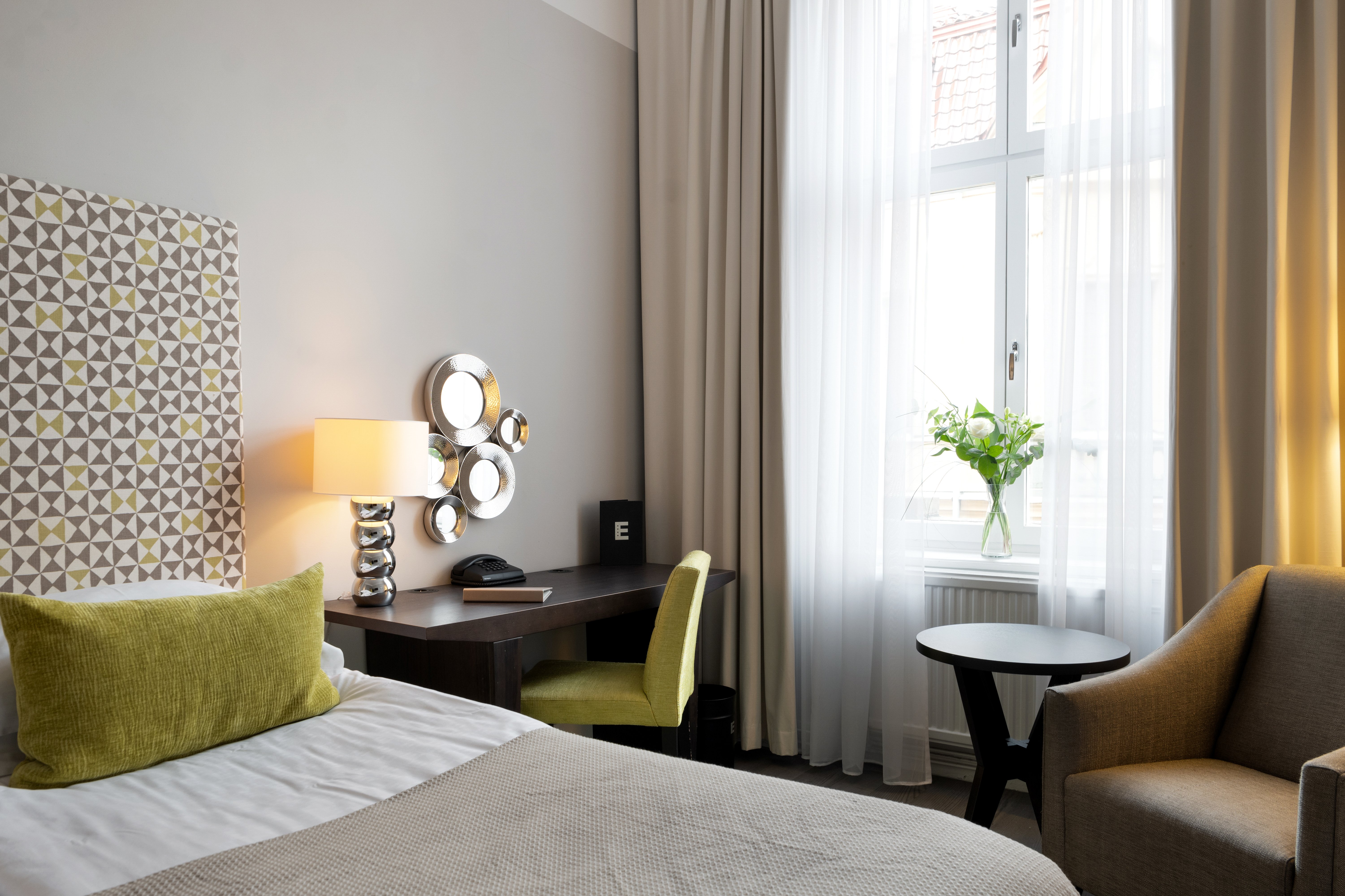 Hotel room with bed, desk and armchair