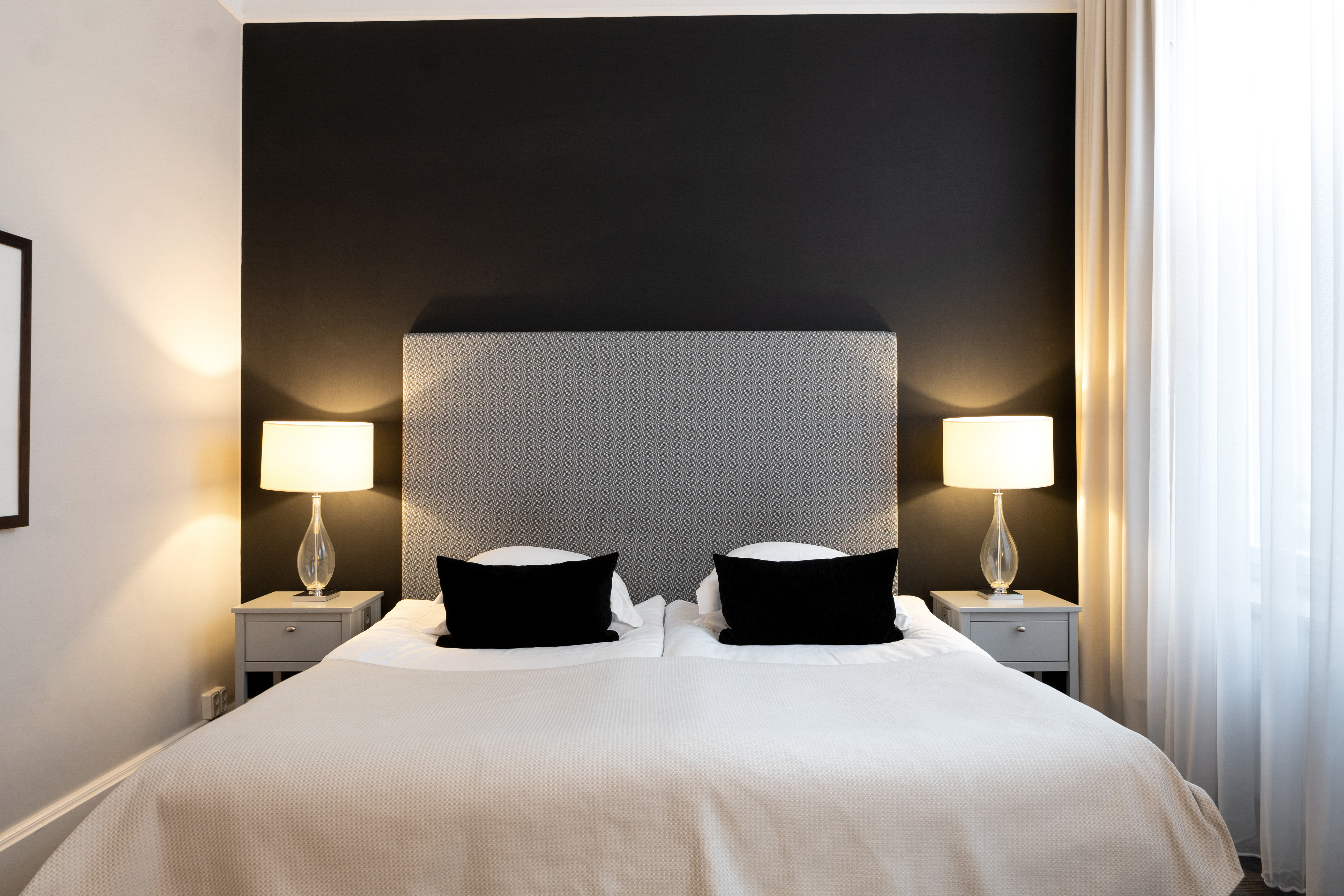 Hotel room with black wall, bed and bedside lamps