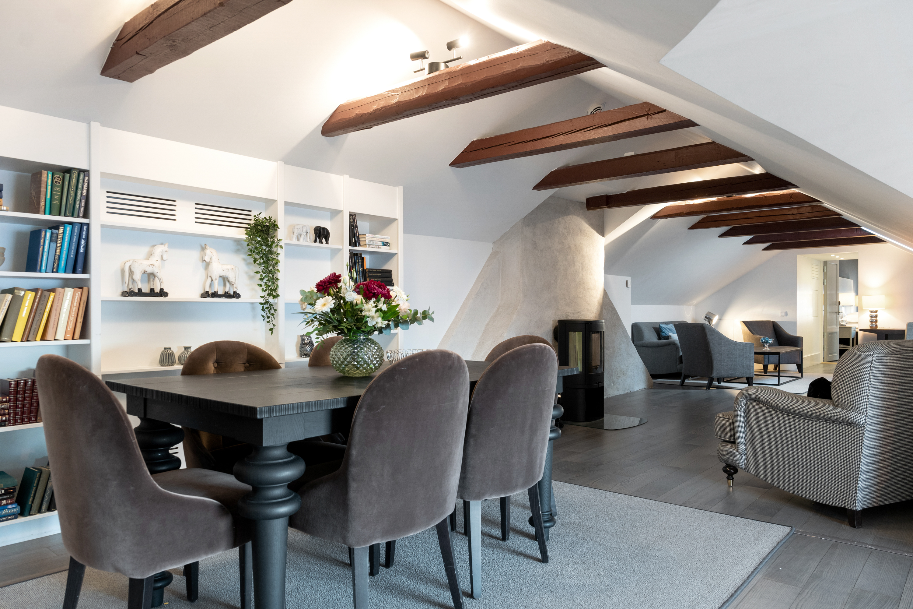 Bright suite with dining table, bookcase and wooden beams in the ceiling