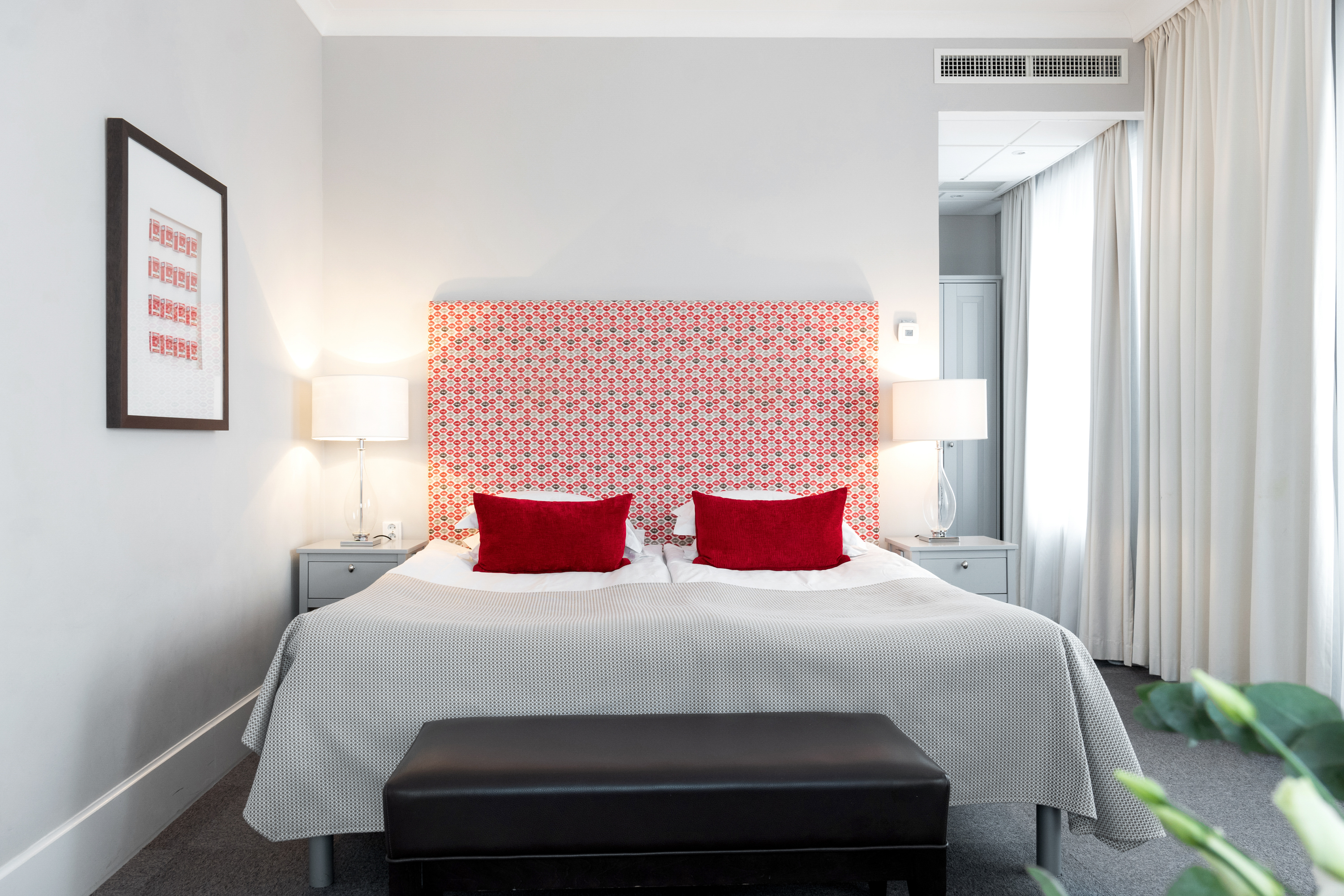 Bright suite with double bed, red pillows and bedside lamps