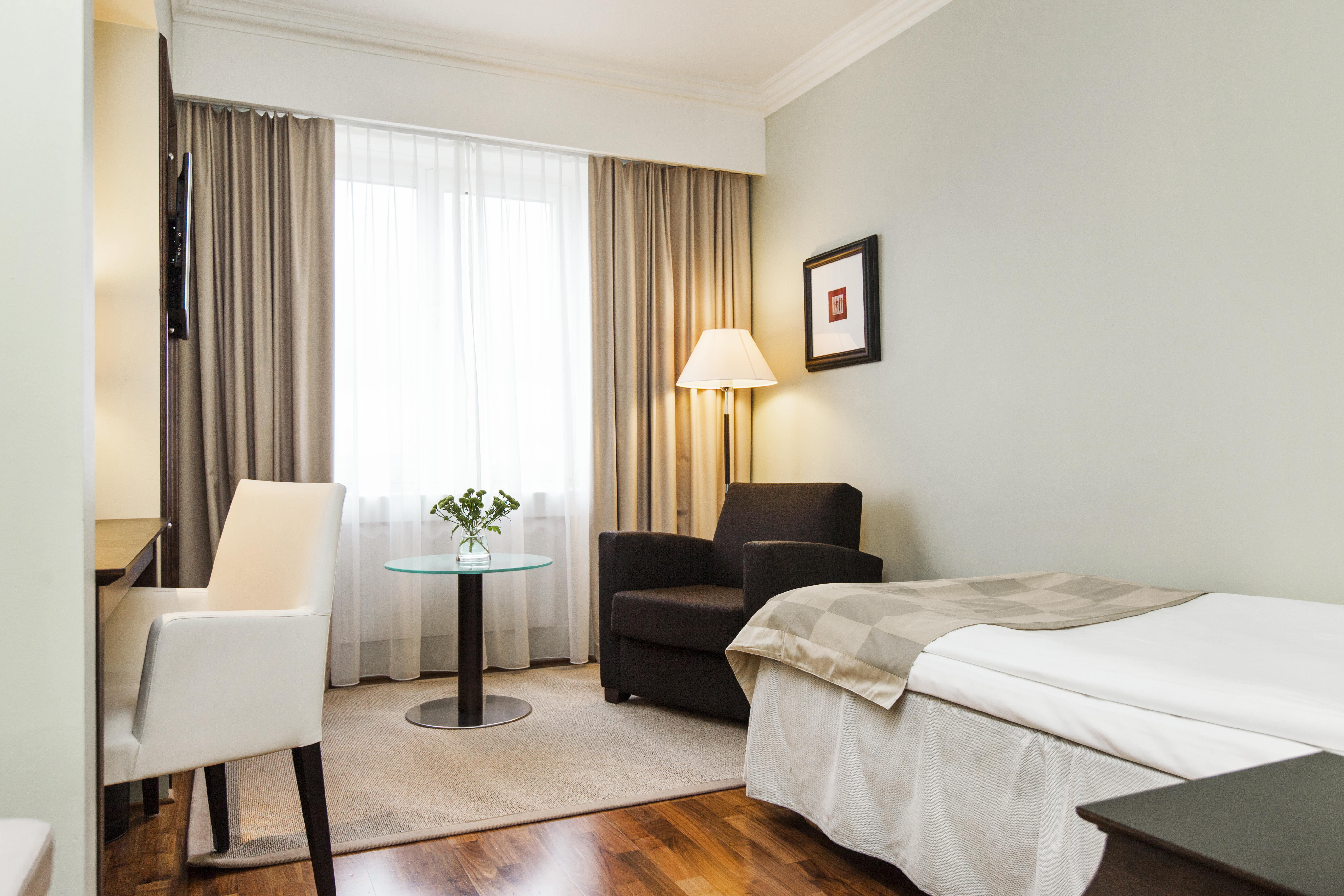 Cozy hotel room with single bed, armchair and desk