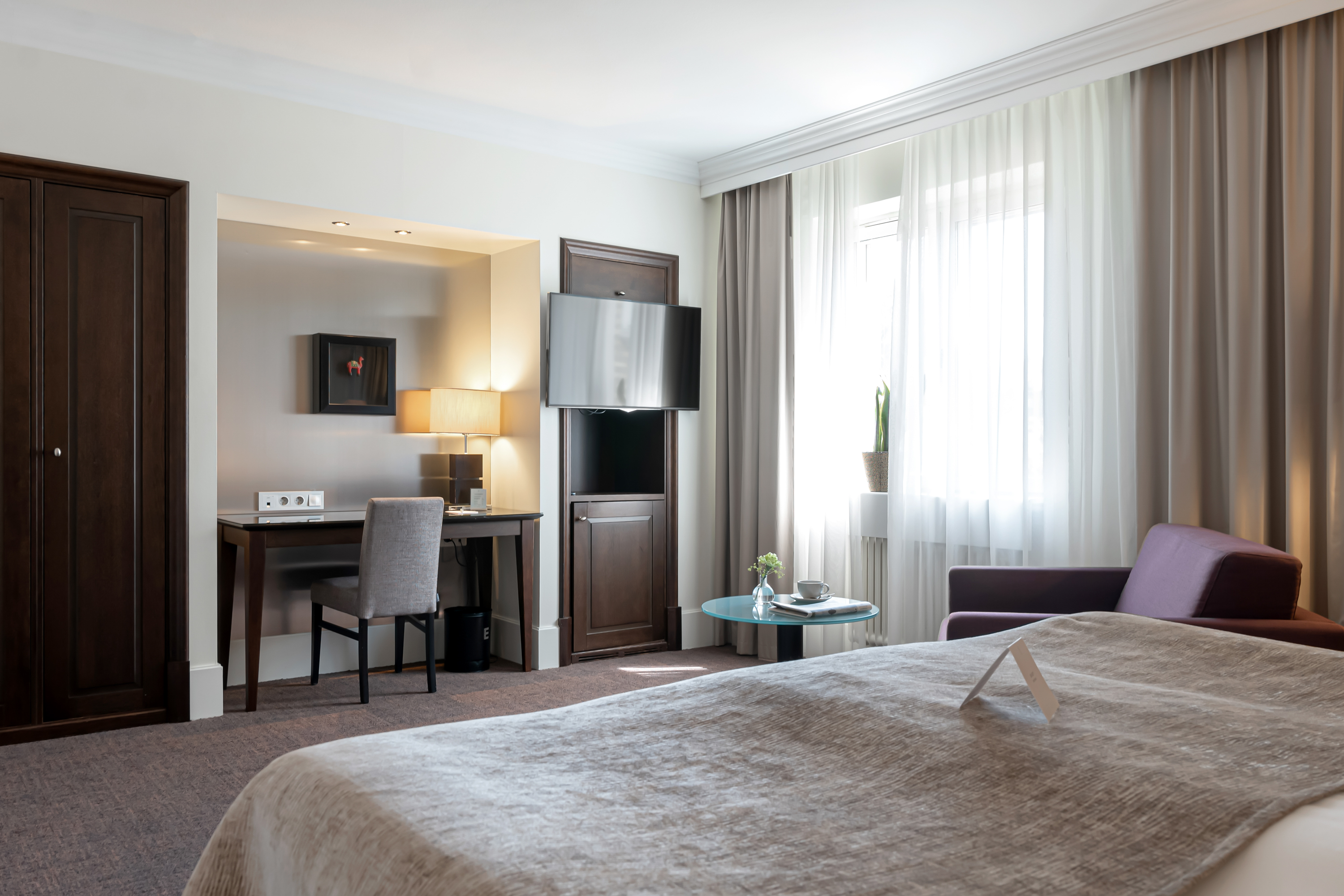 Hotel room with armchair, desk and TV