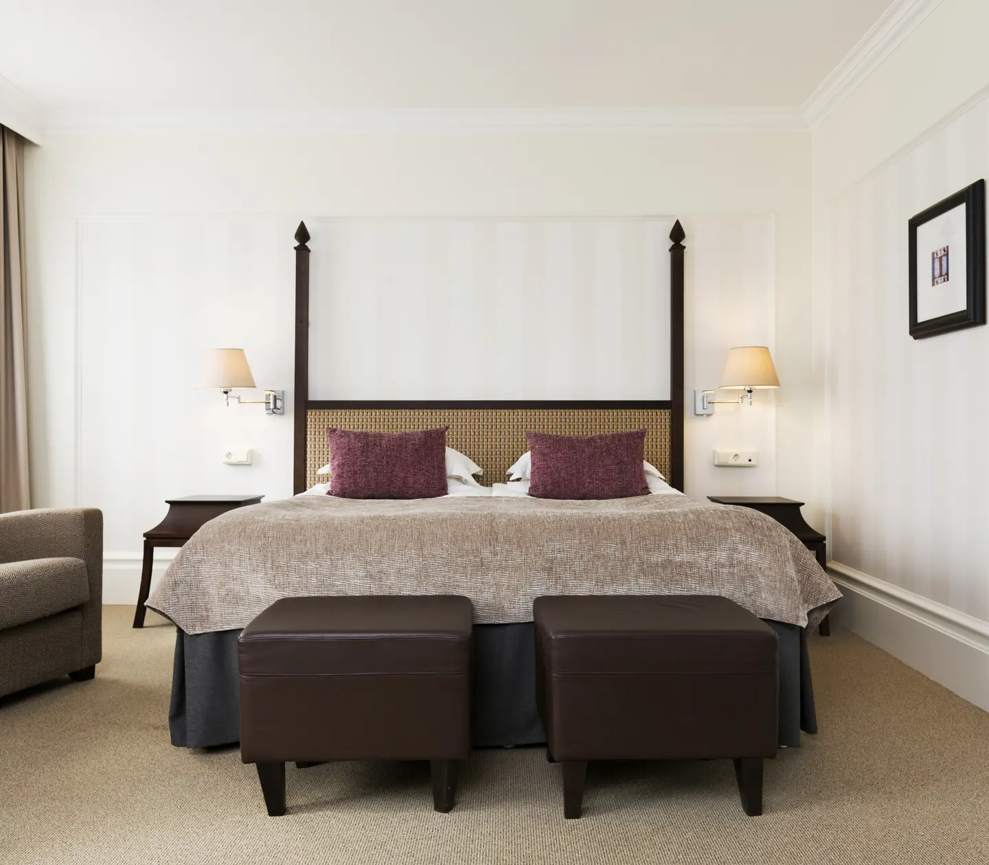 Cozy hotel room with double bed, armchairs and footstools