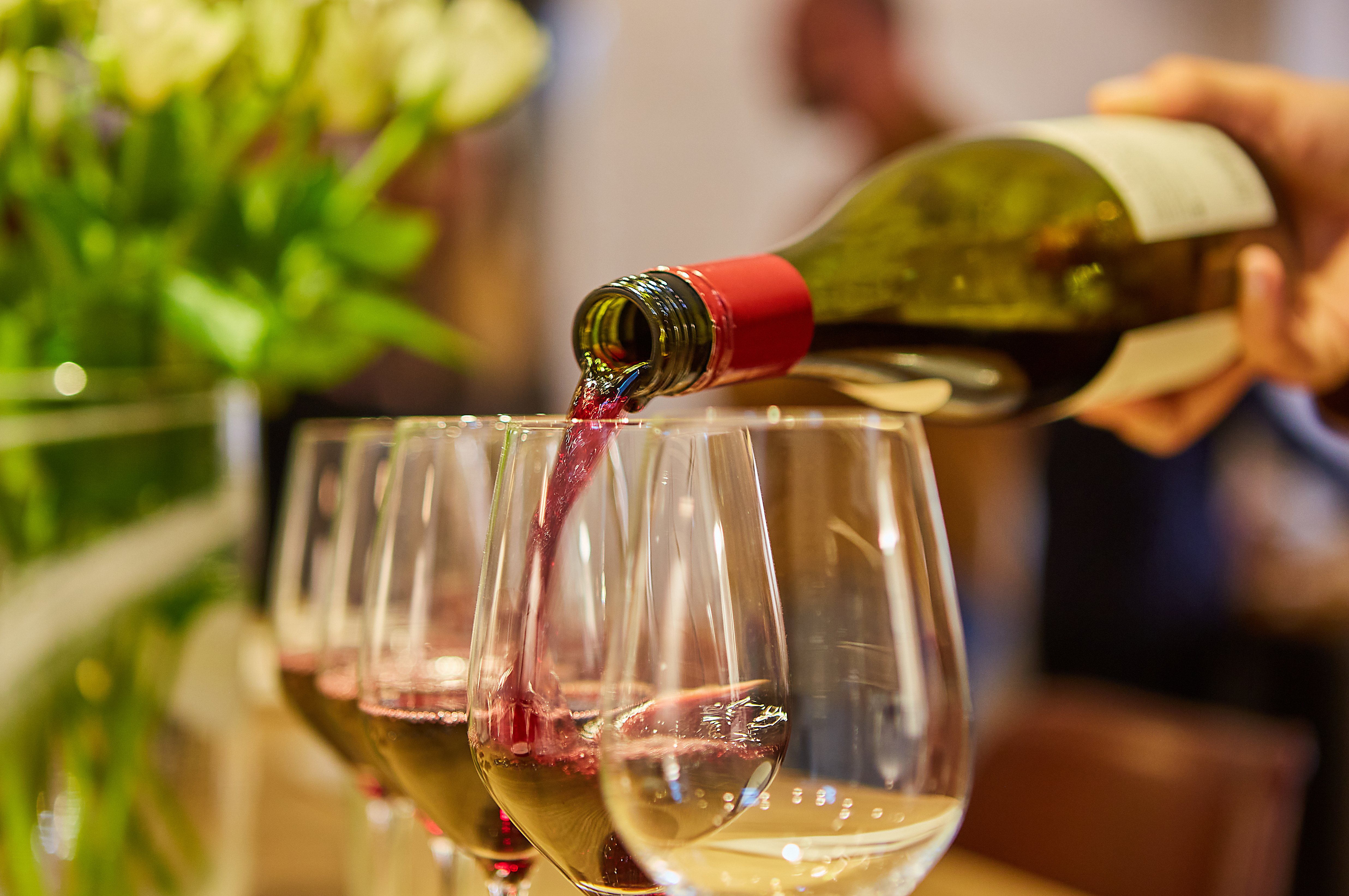 Person som häller upp rödvin från flaska