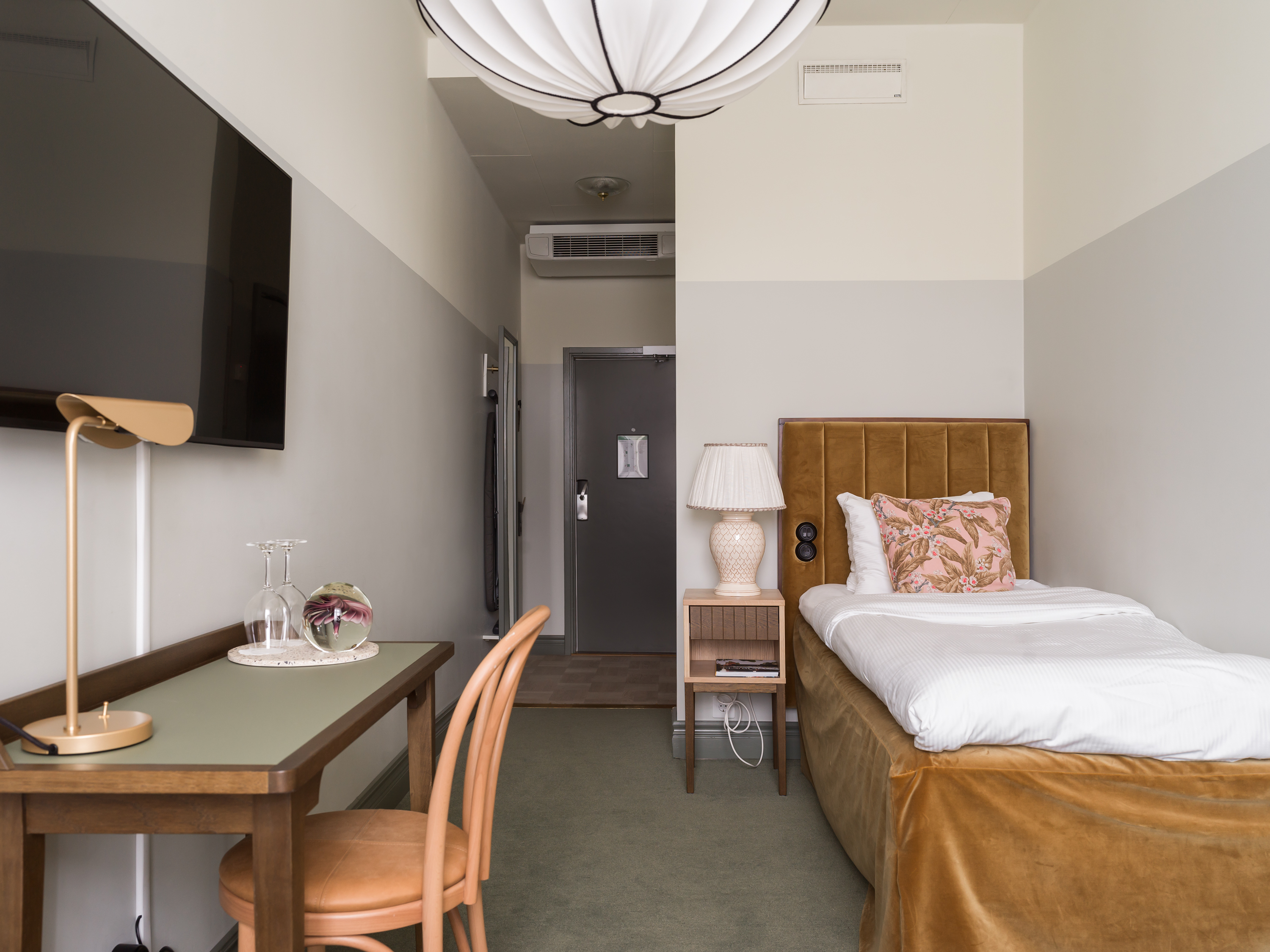 Enkelsäng och skrivbord med stol under tv i hotellrum