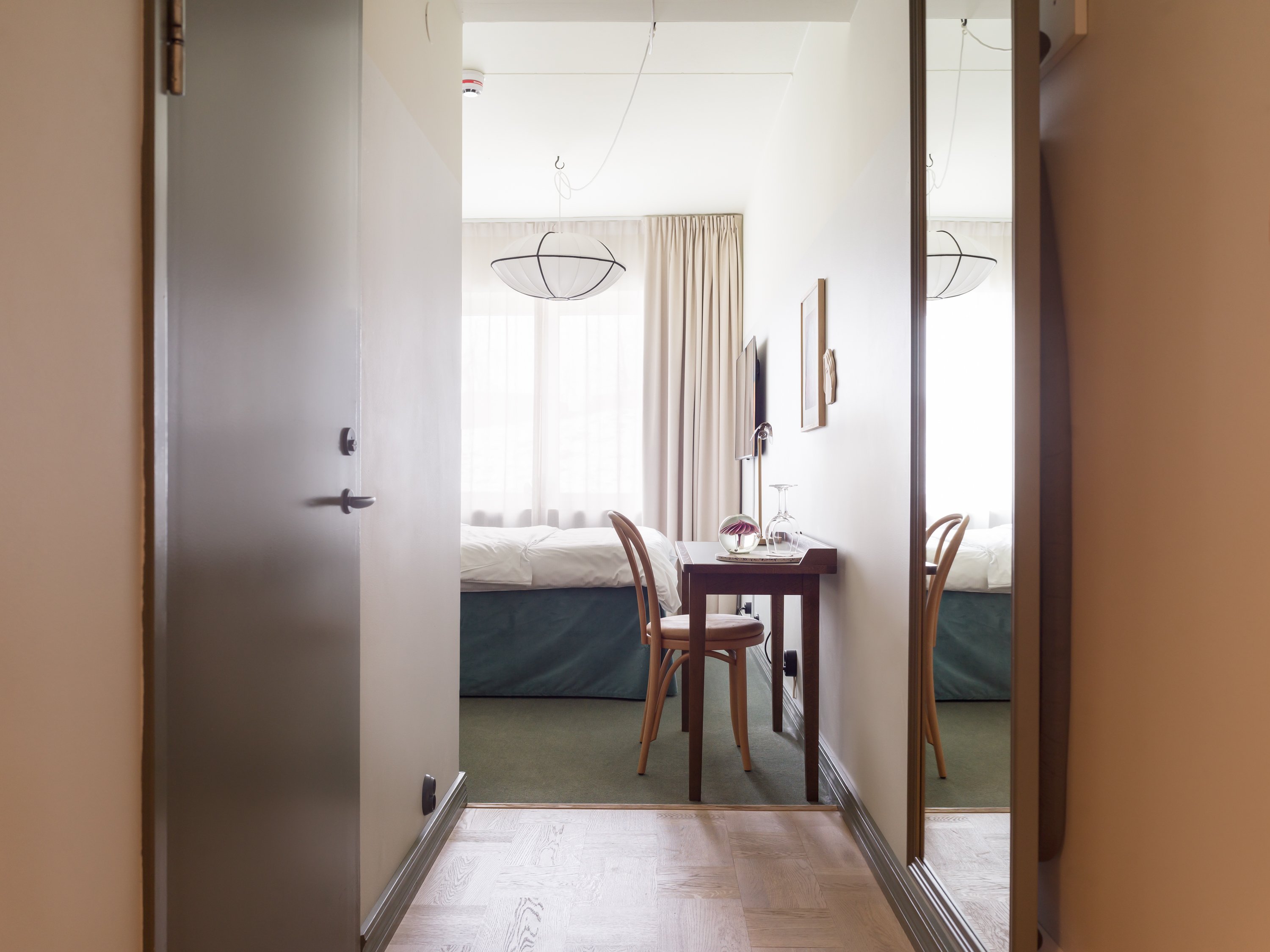 Skrivbord och stol som syns från hall i hotellrum