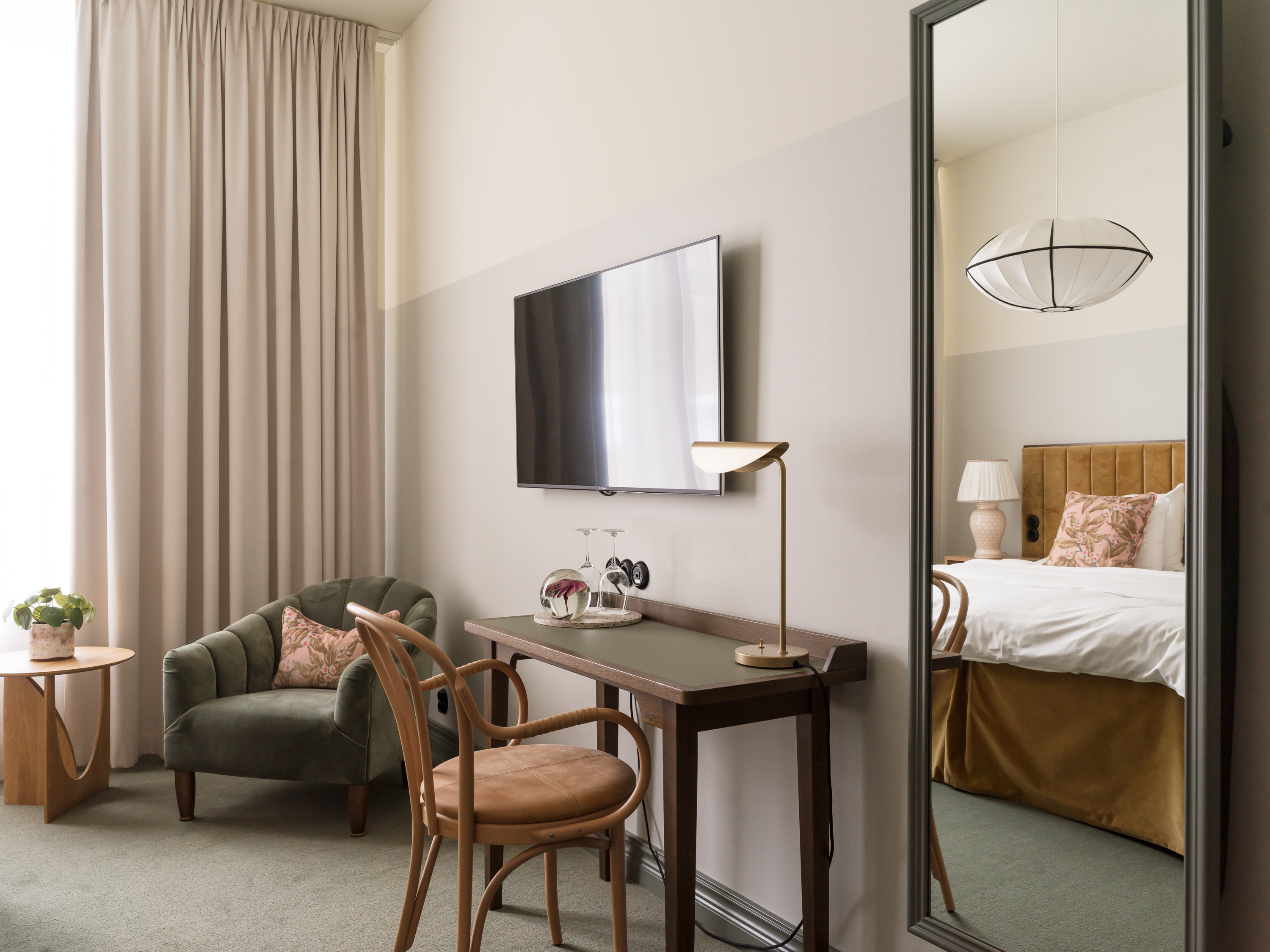 Skrivbord, tv, fåtölj och spegel i rum