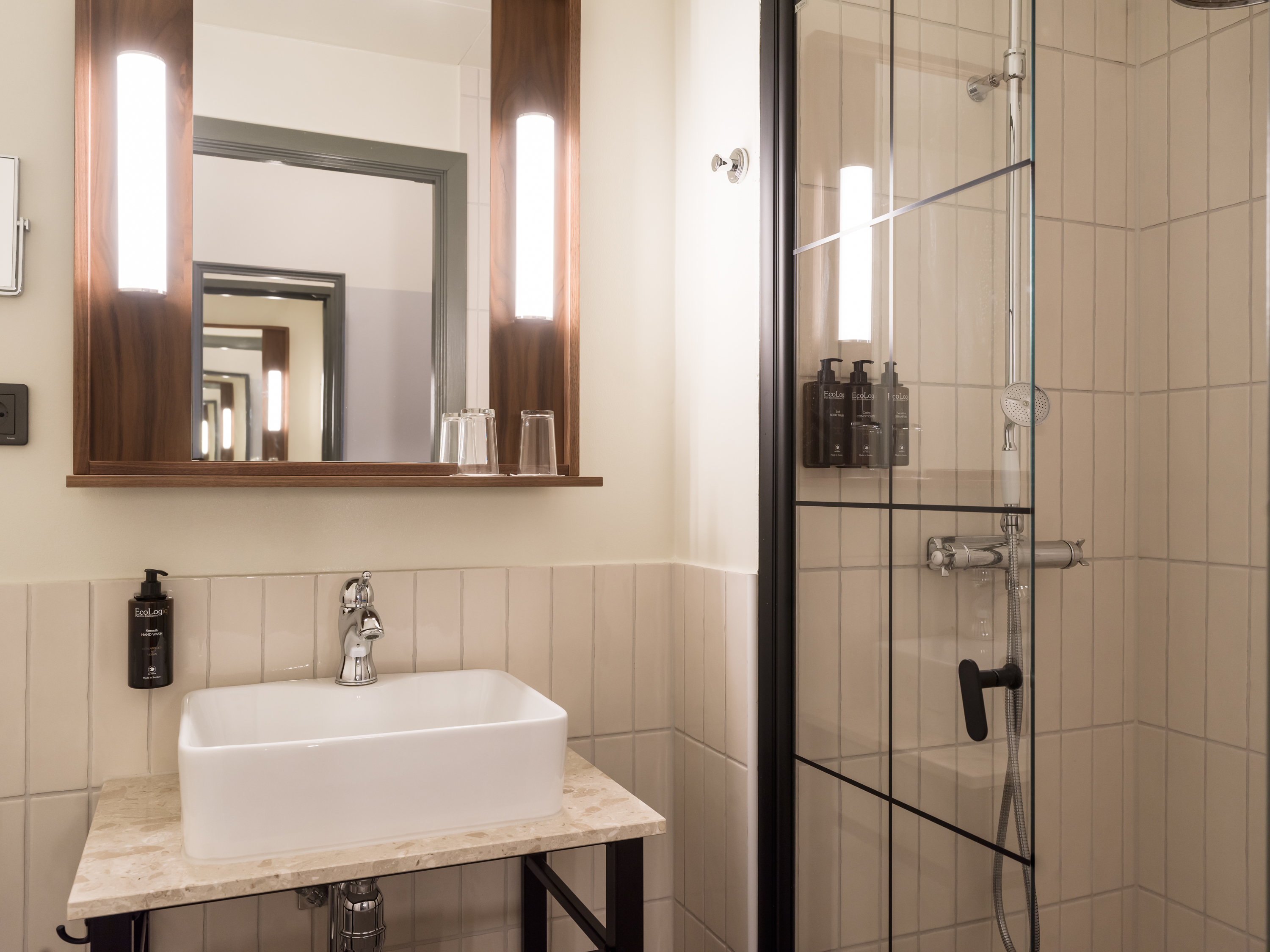 Handfat, spegel och dusch i badrum