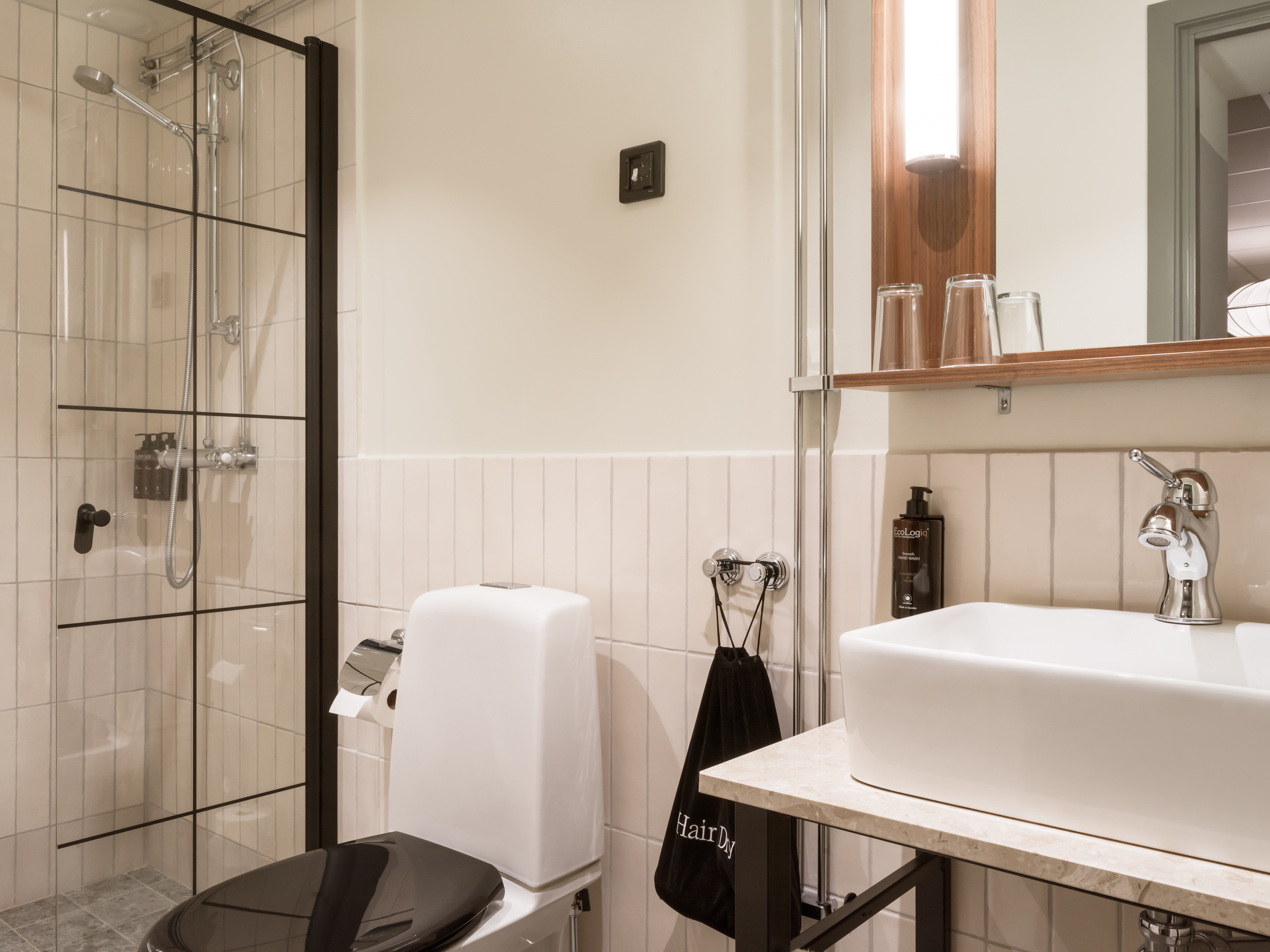 Toalett, handfat, spegel och dusch i badrum