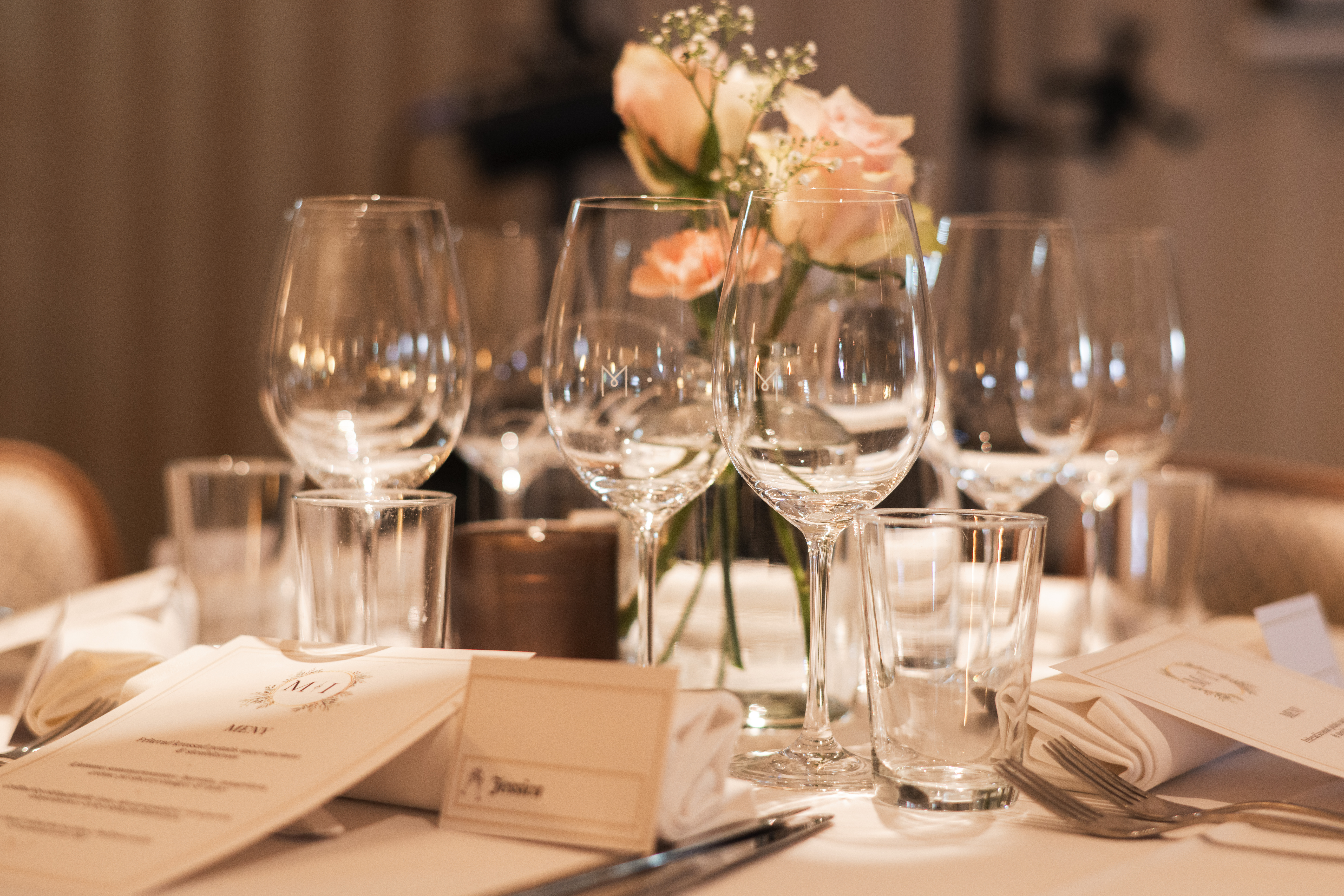 Elegant wedding table setting with white linens, wine glasses, and green ivy centerpiece. Candles add a romantic ambiance in a finely decorated room.