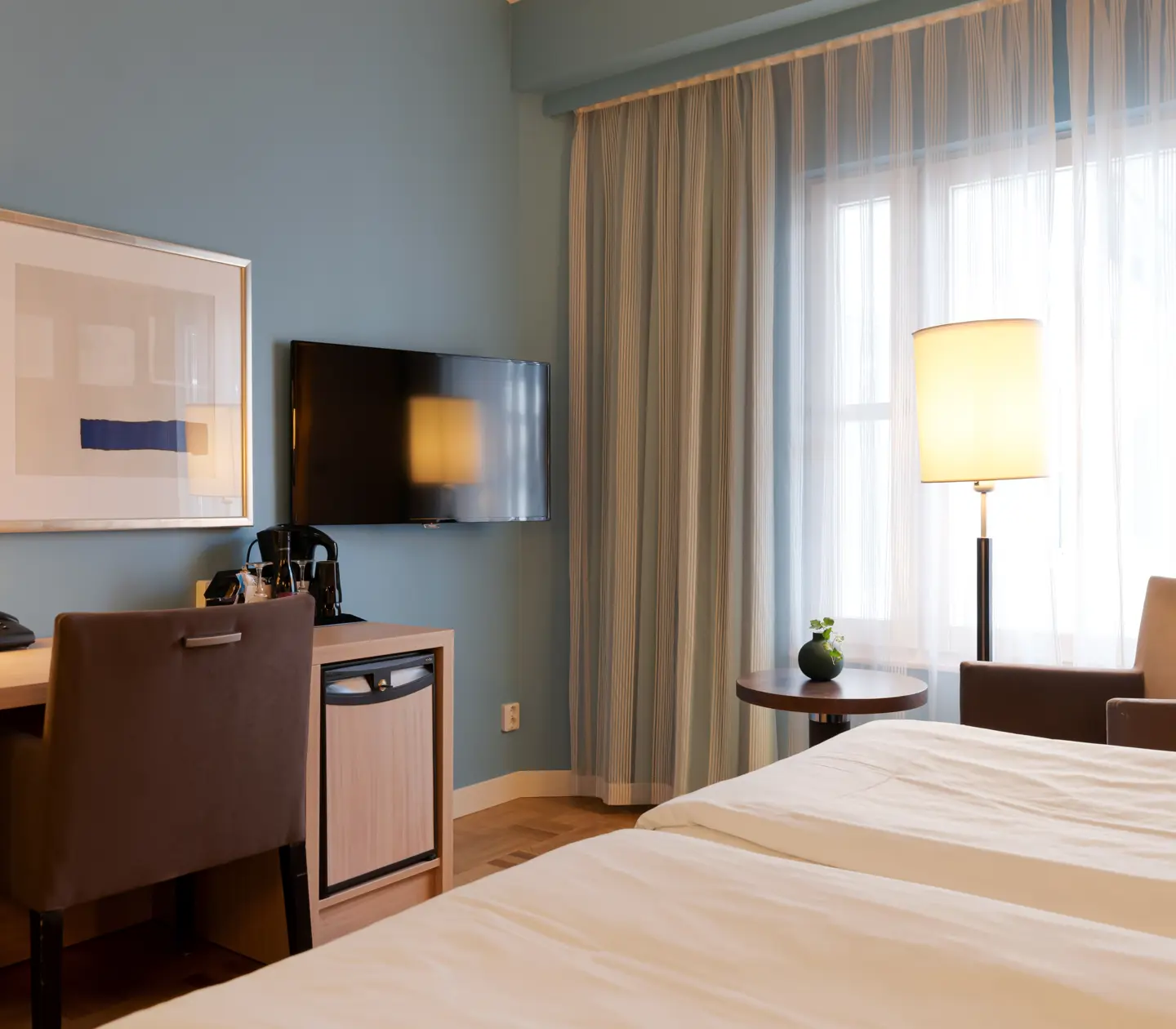 Hotellrum med fåtölj, skrivbord och tv