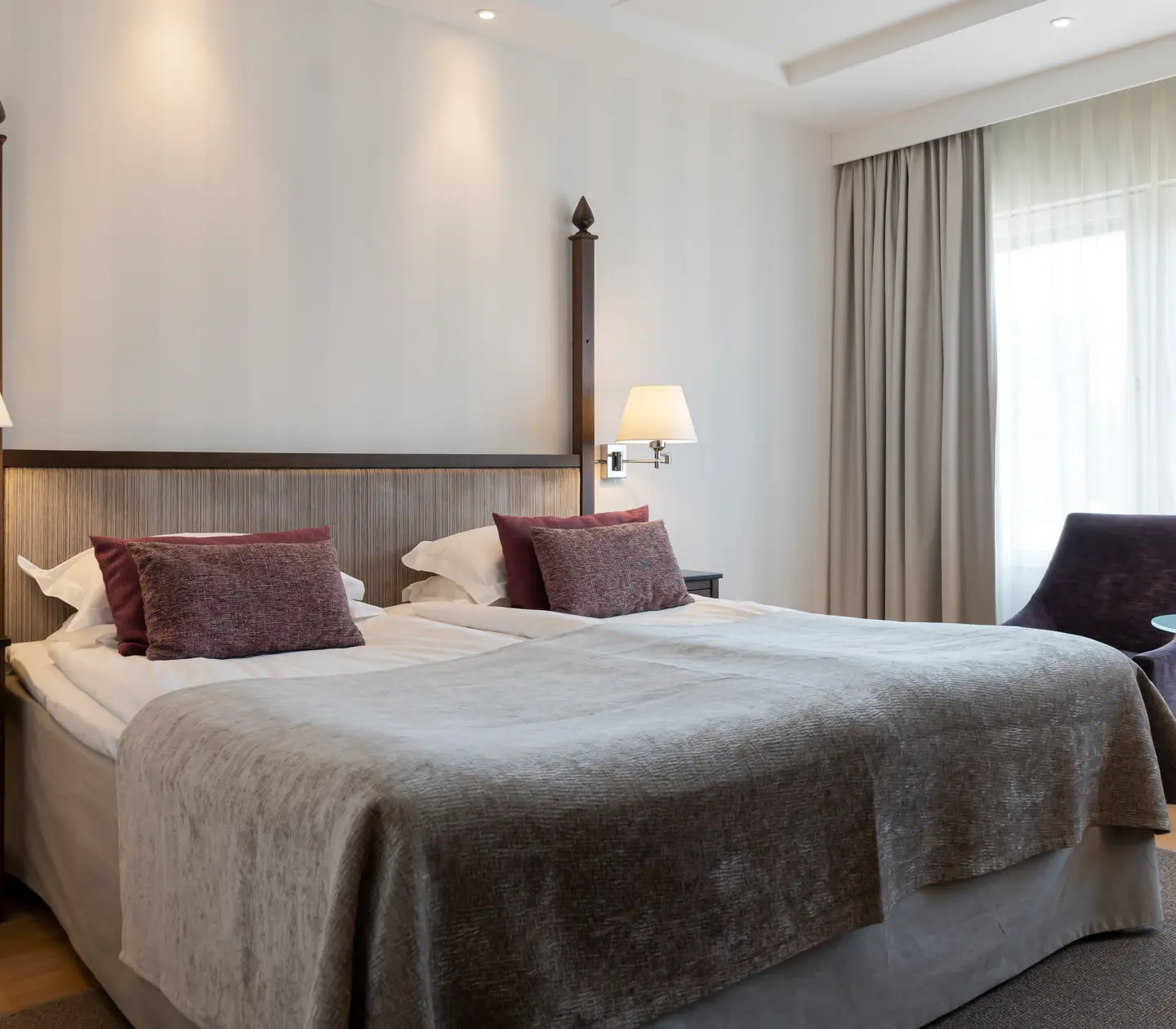 Ljust hotellrum med dubbelsäng, fåtöljer och fönster
