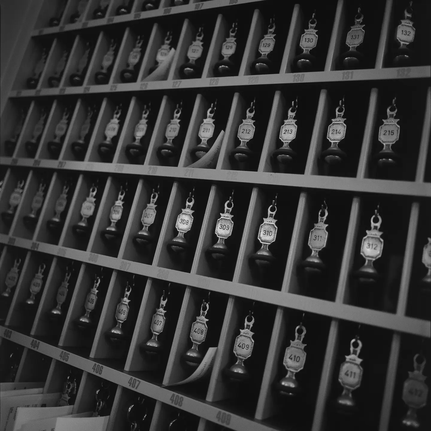 Svartvit bild av äldre nycklar i skåp