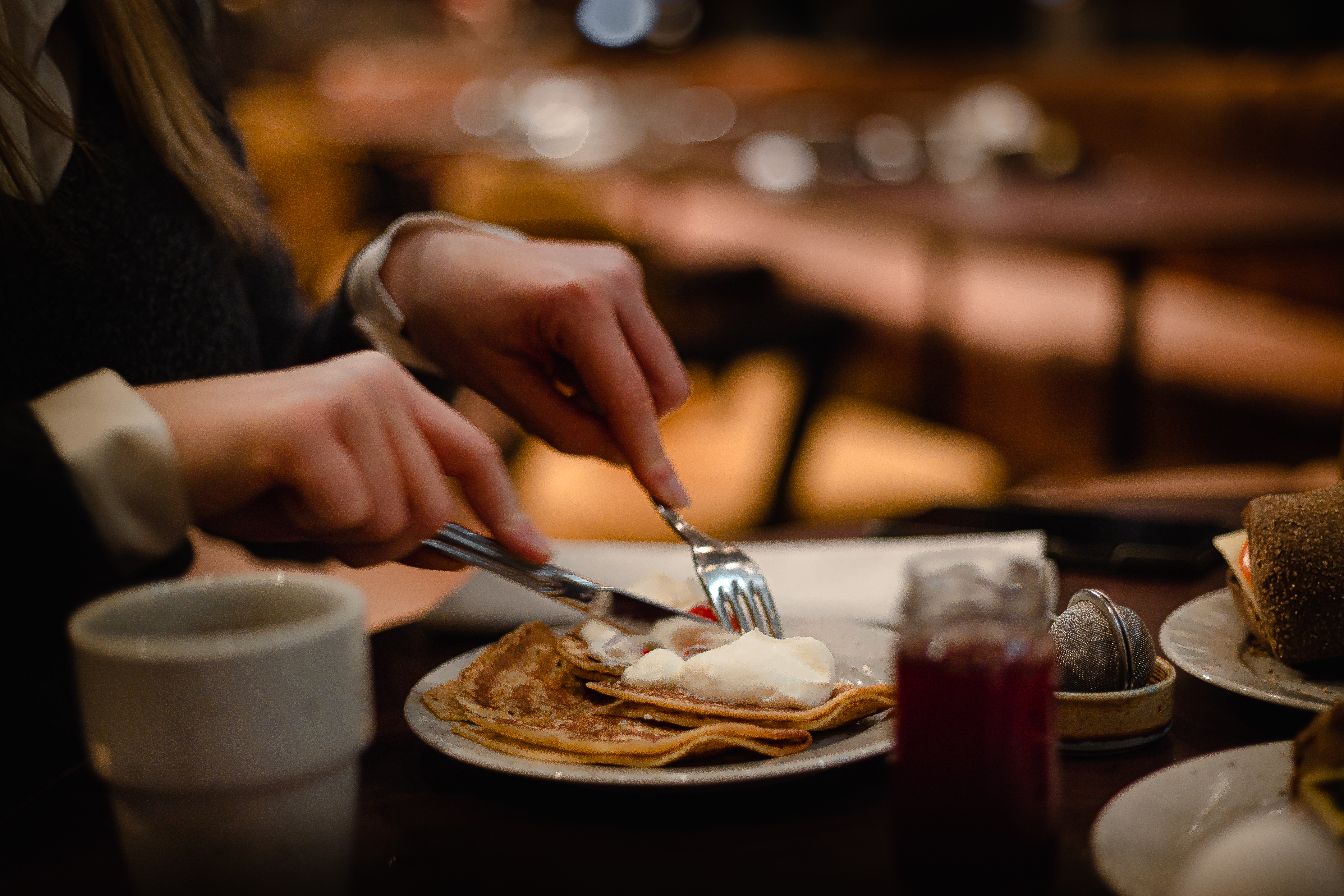 Restauranginteriör med eleganta rosa soffor och dekorativa växter, omgiven av stora välvda fönster och lyxig inredning.