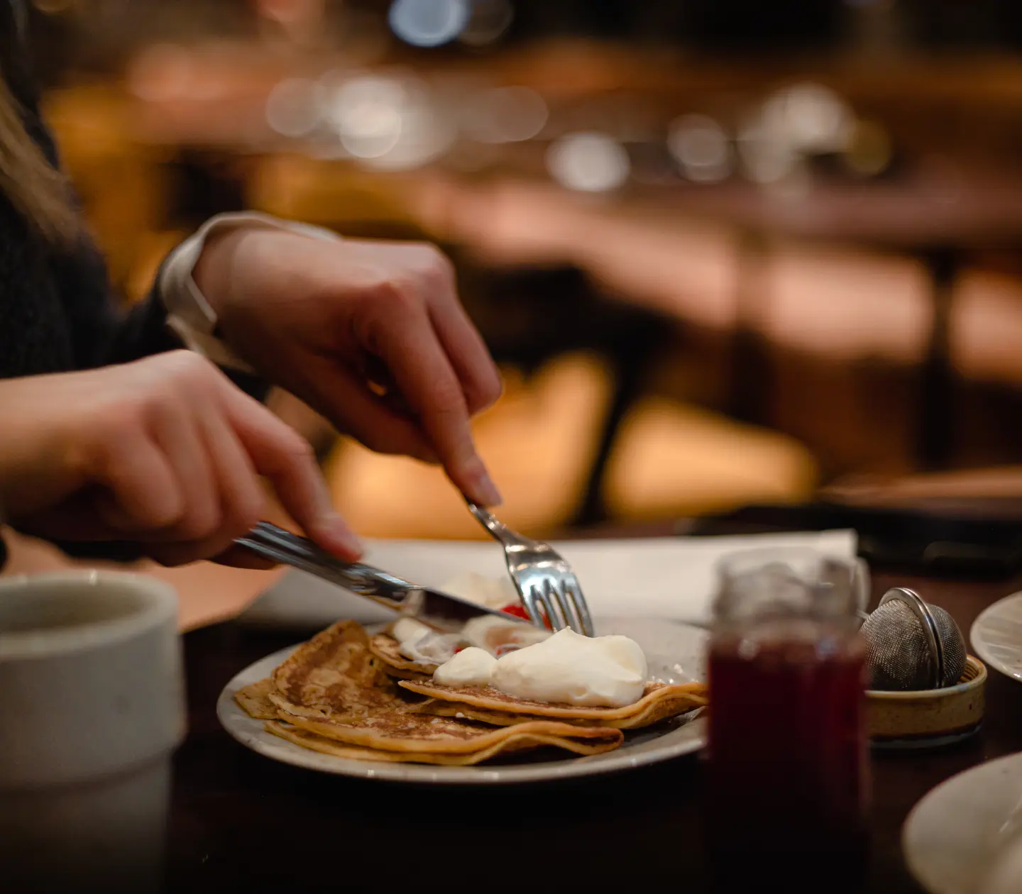 Restauranginteriör med eleganta rosa soffor och dekorativa växter, omgiven av stora välvda fönster och lyxig inredning.