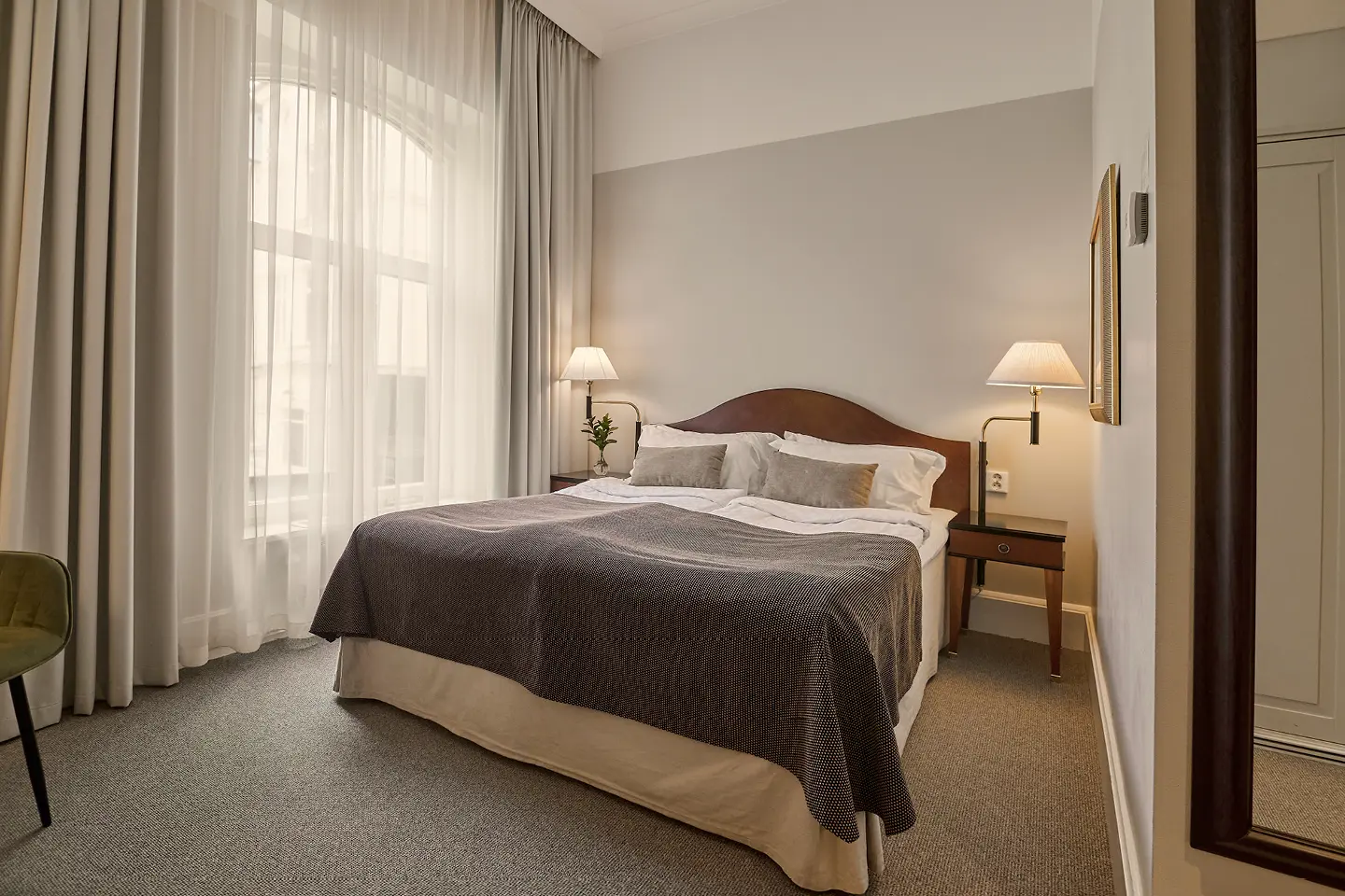 Cozy hotel room with twin beds featuring red patterned headboards, white bedding, and red accent pillows. Modern bedside tables with glass lamps add elegance.
