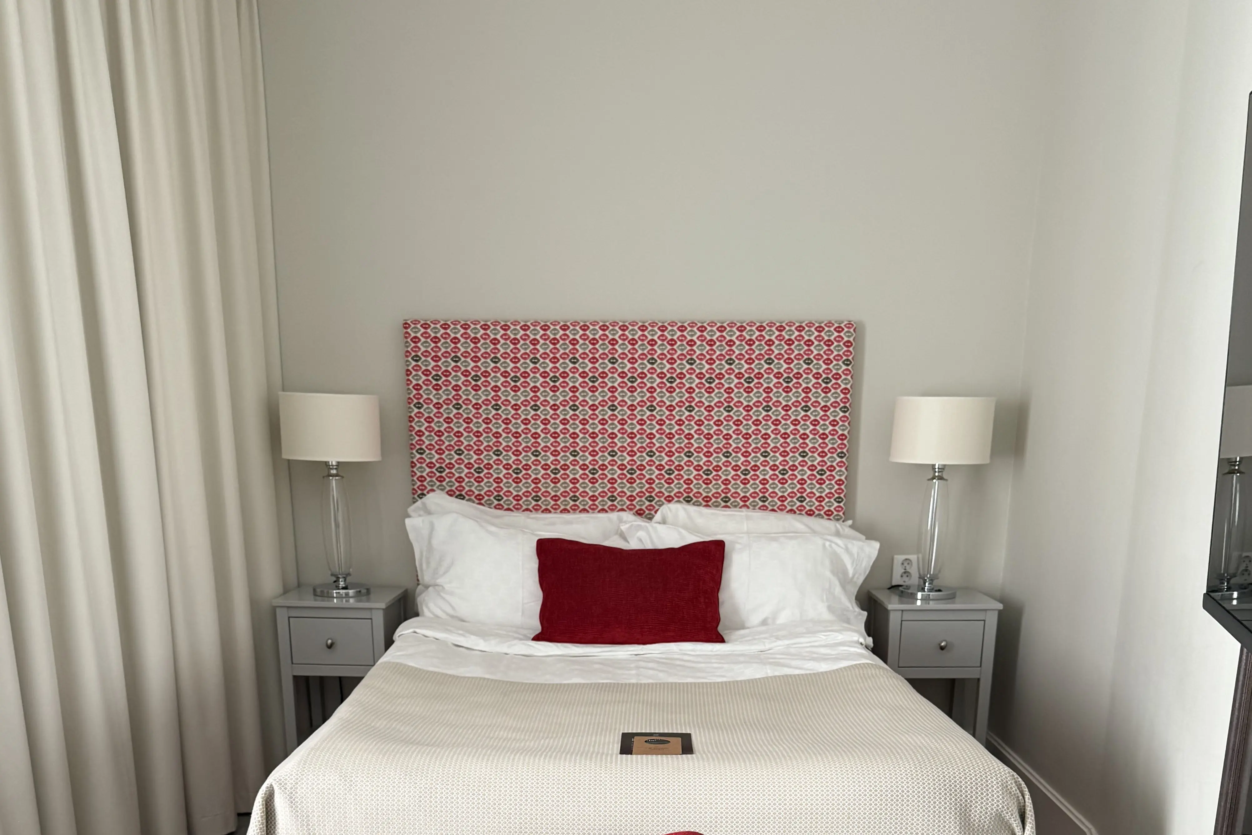 Hotellrum med dubbelsäng, röd sänggavel och skrivbord