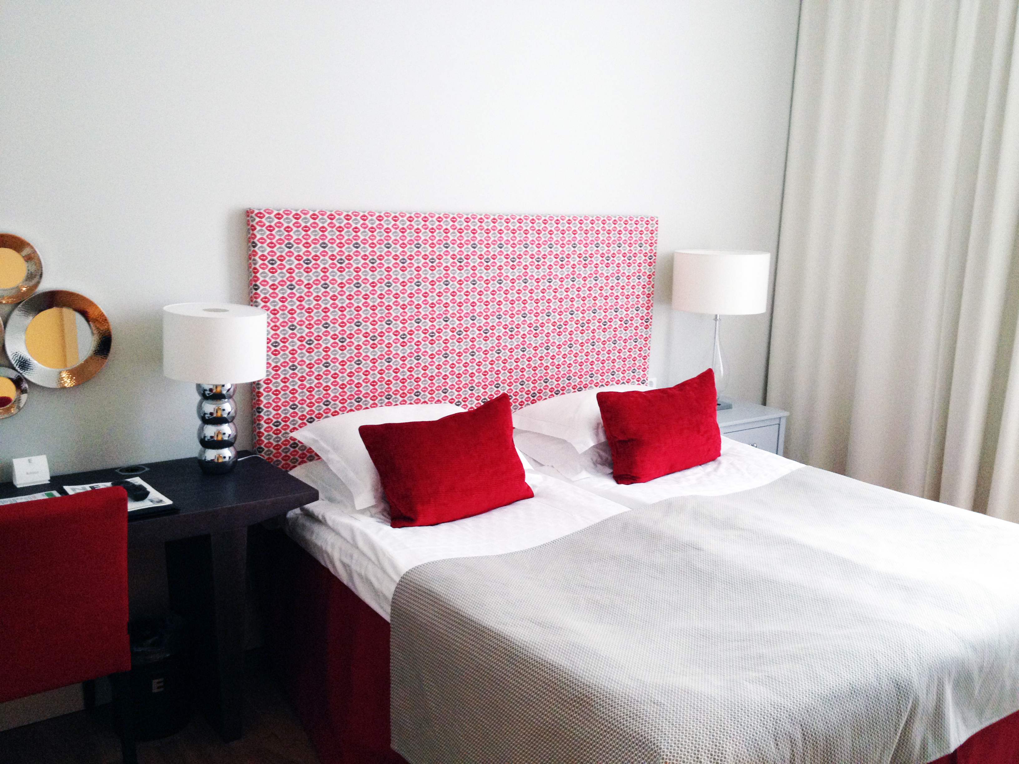Hotel room with double bed, red headboard and desk