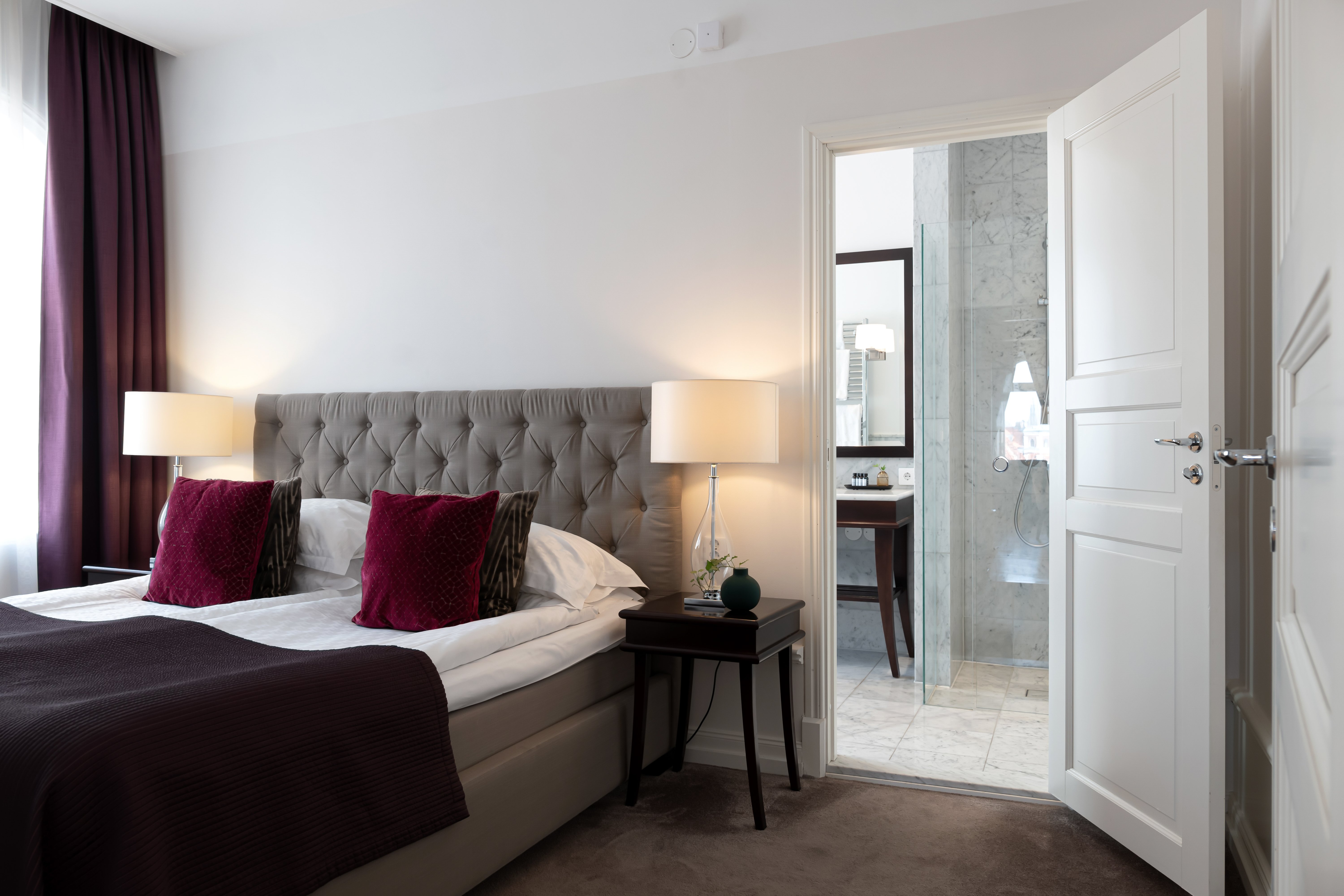 Suite with double bed, bedside lamps and door to bathroom