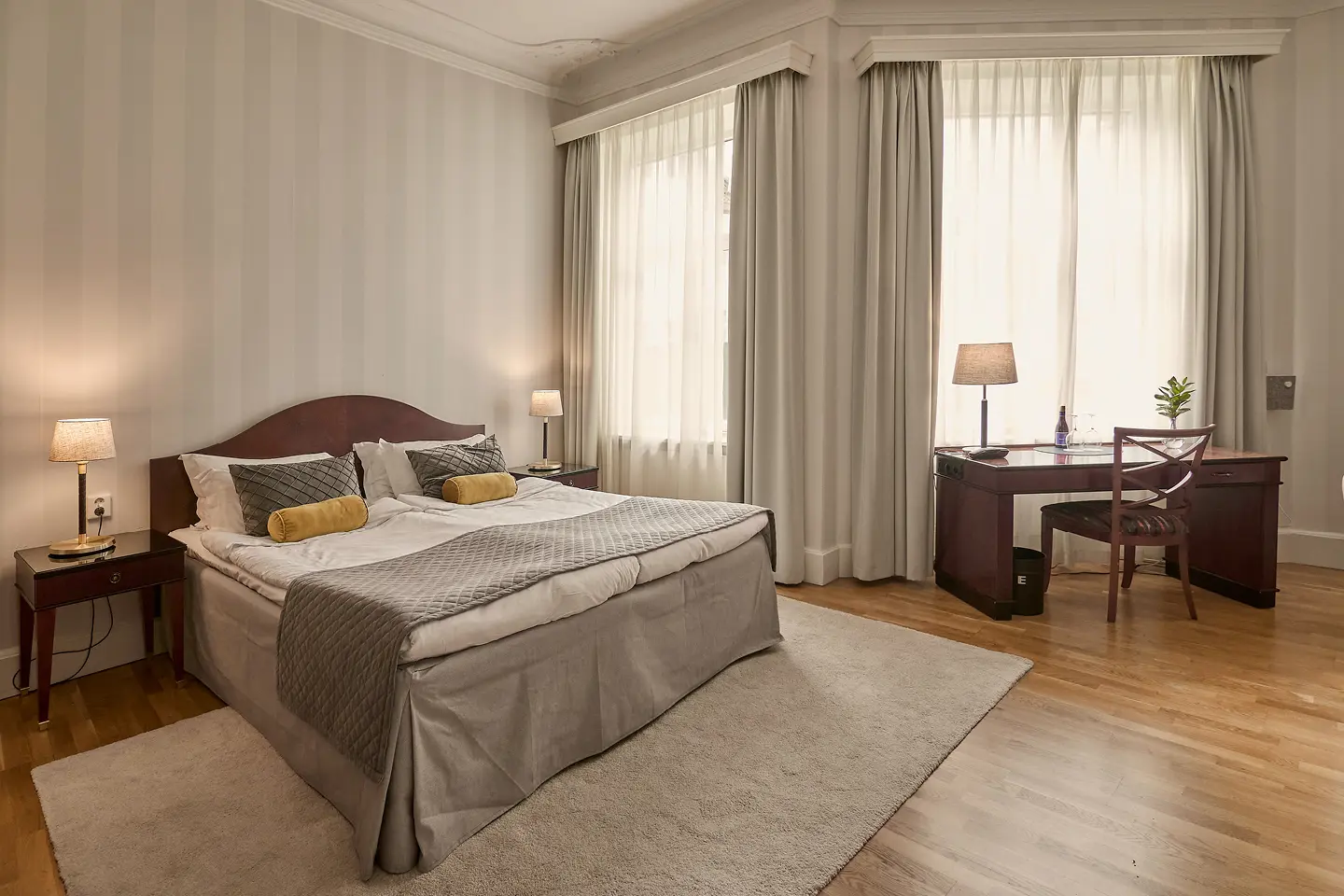 Suite with double bed, seating area and green tiled stove