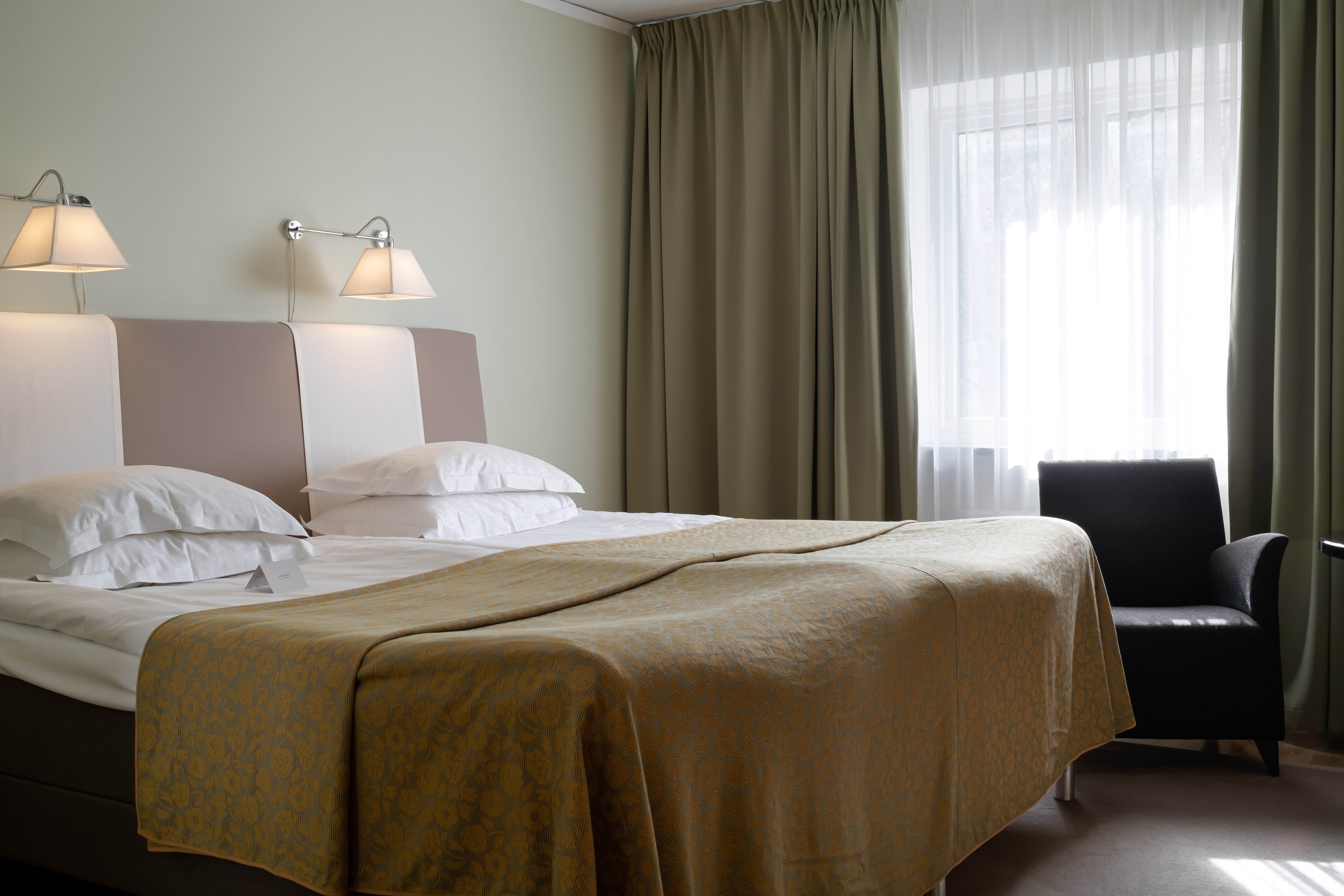 Hotel room with bed, armchair and curtains