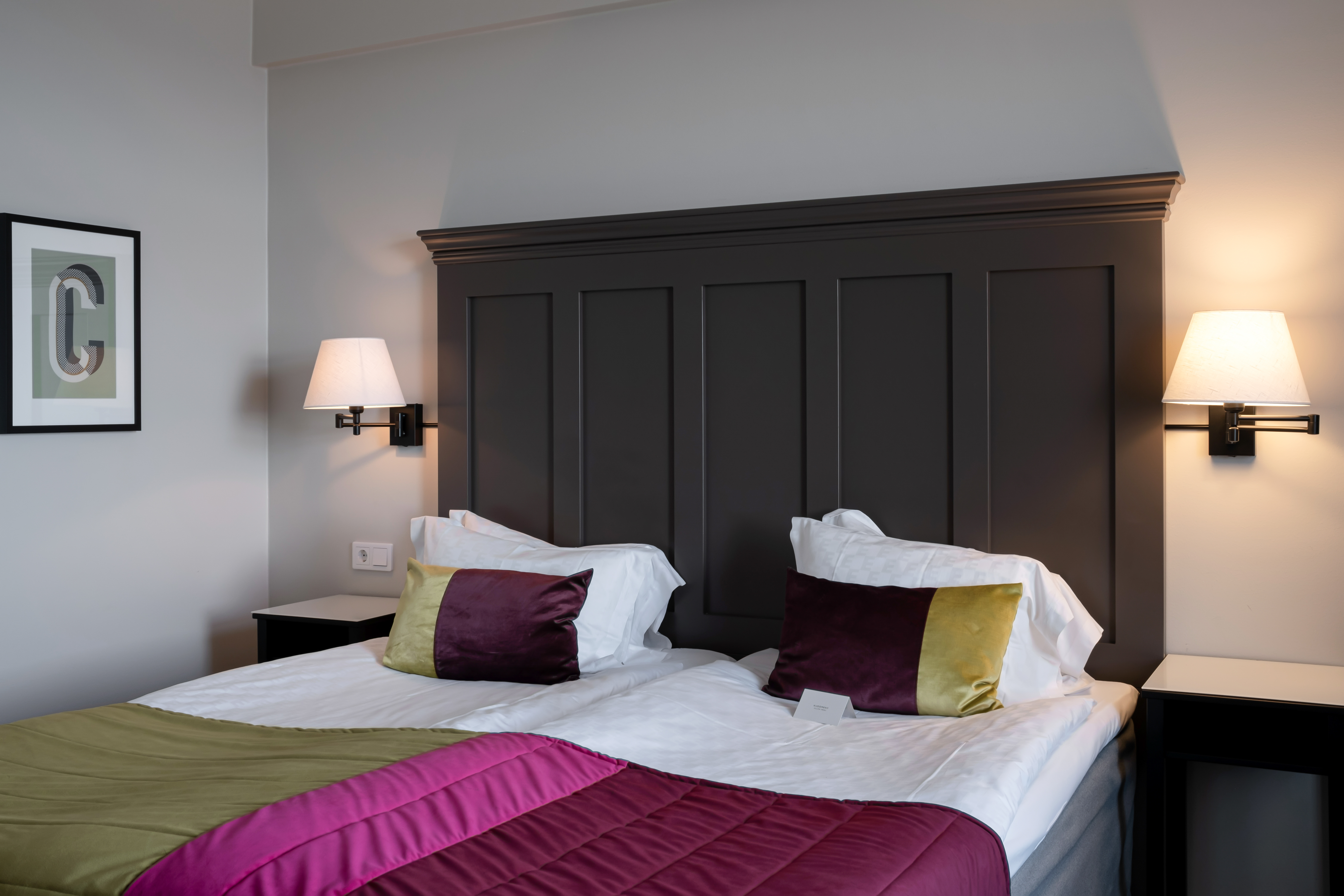 Hotel room with bed, large wooden headboard and painting