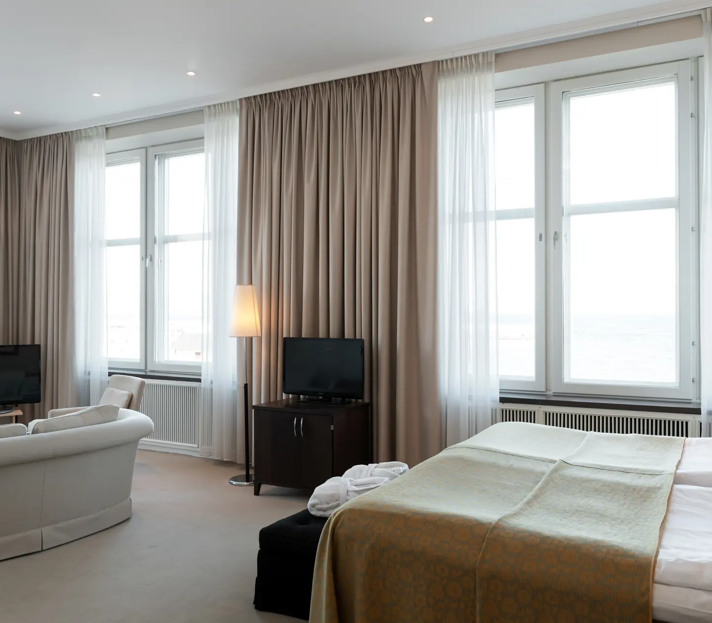Suite with bed, sitting area and large windows
