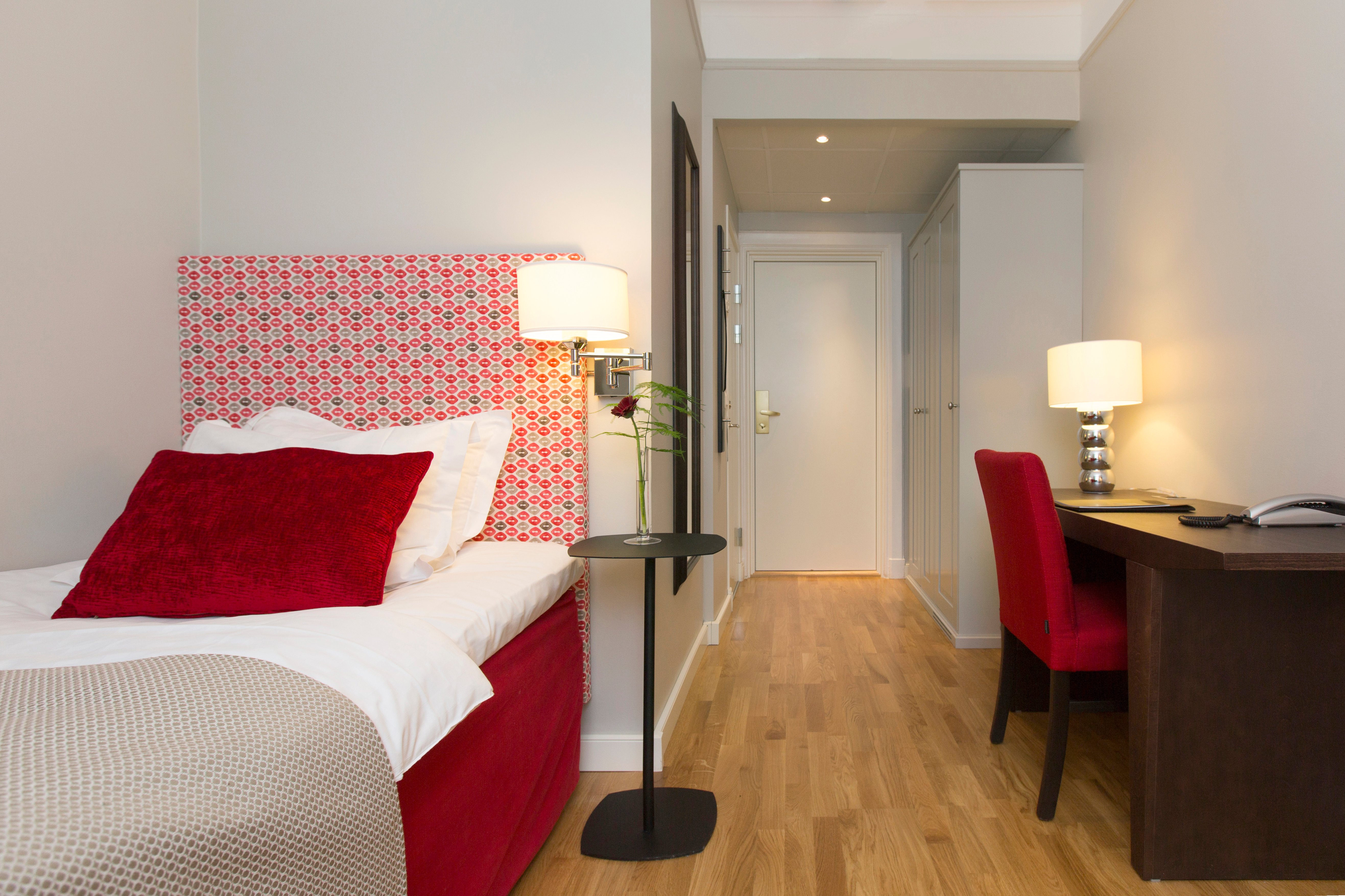 Hotel room with single bed, lamps and desk