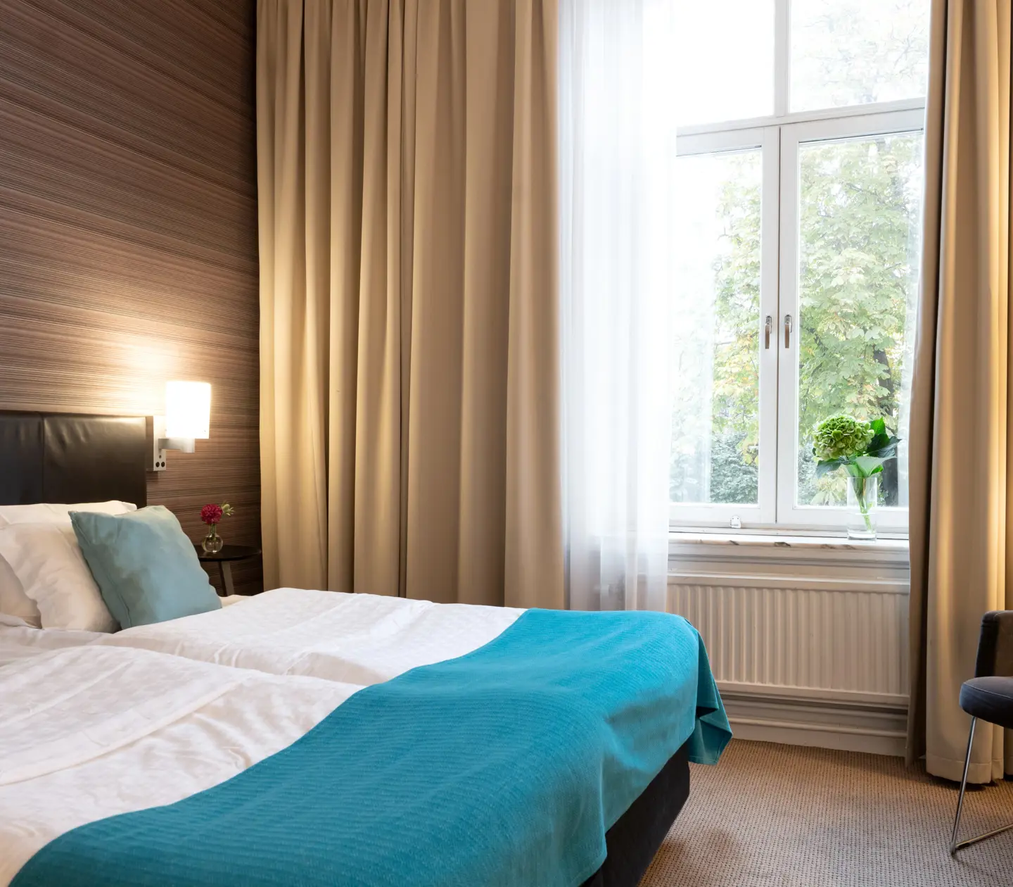Hotellrum med dubbelsäng, fåtölj och fönster