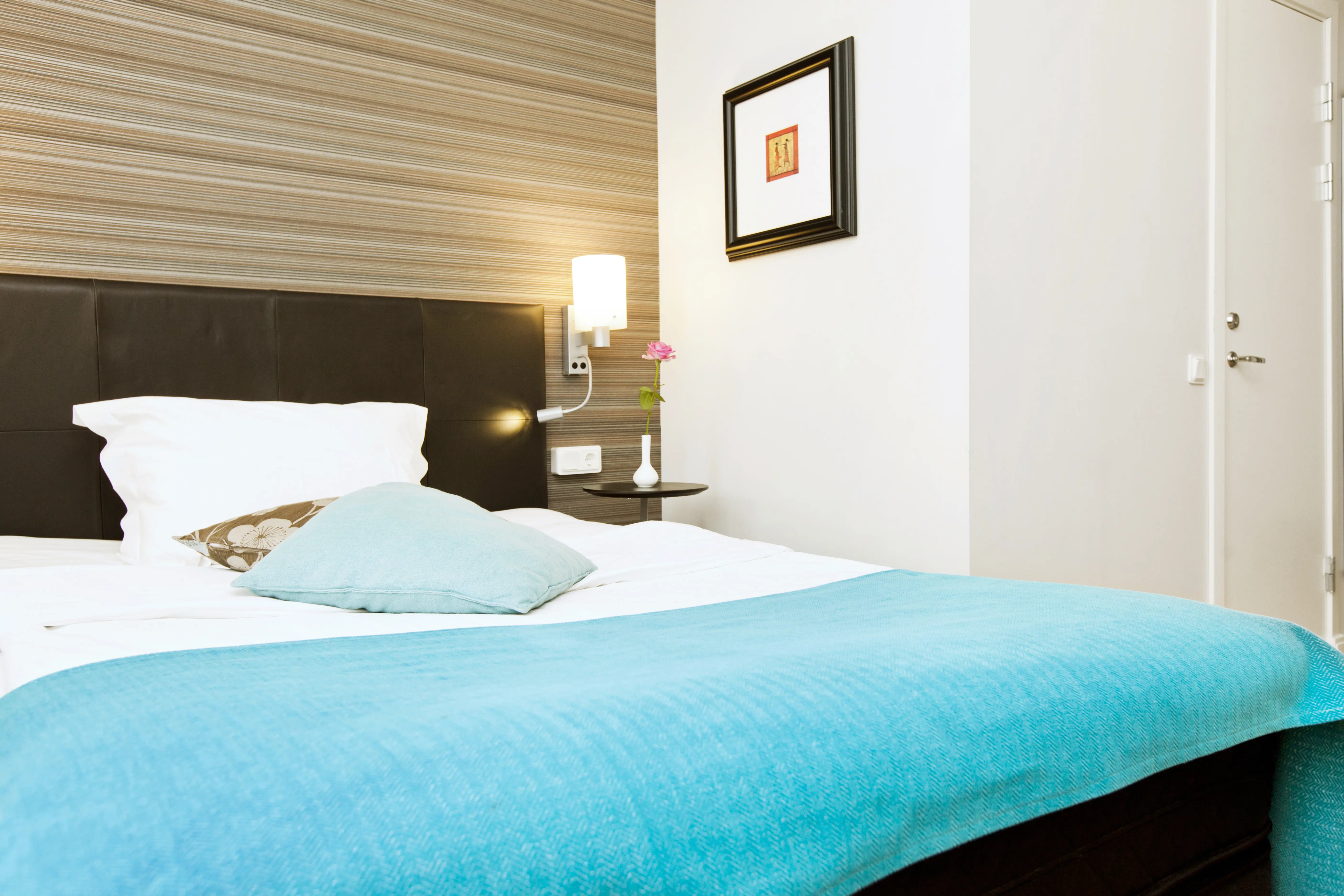 Hotellrum med dubbelsäng, tavla och sänglampa