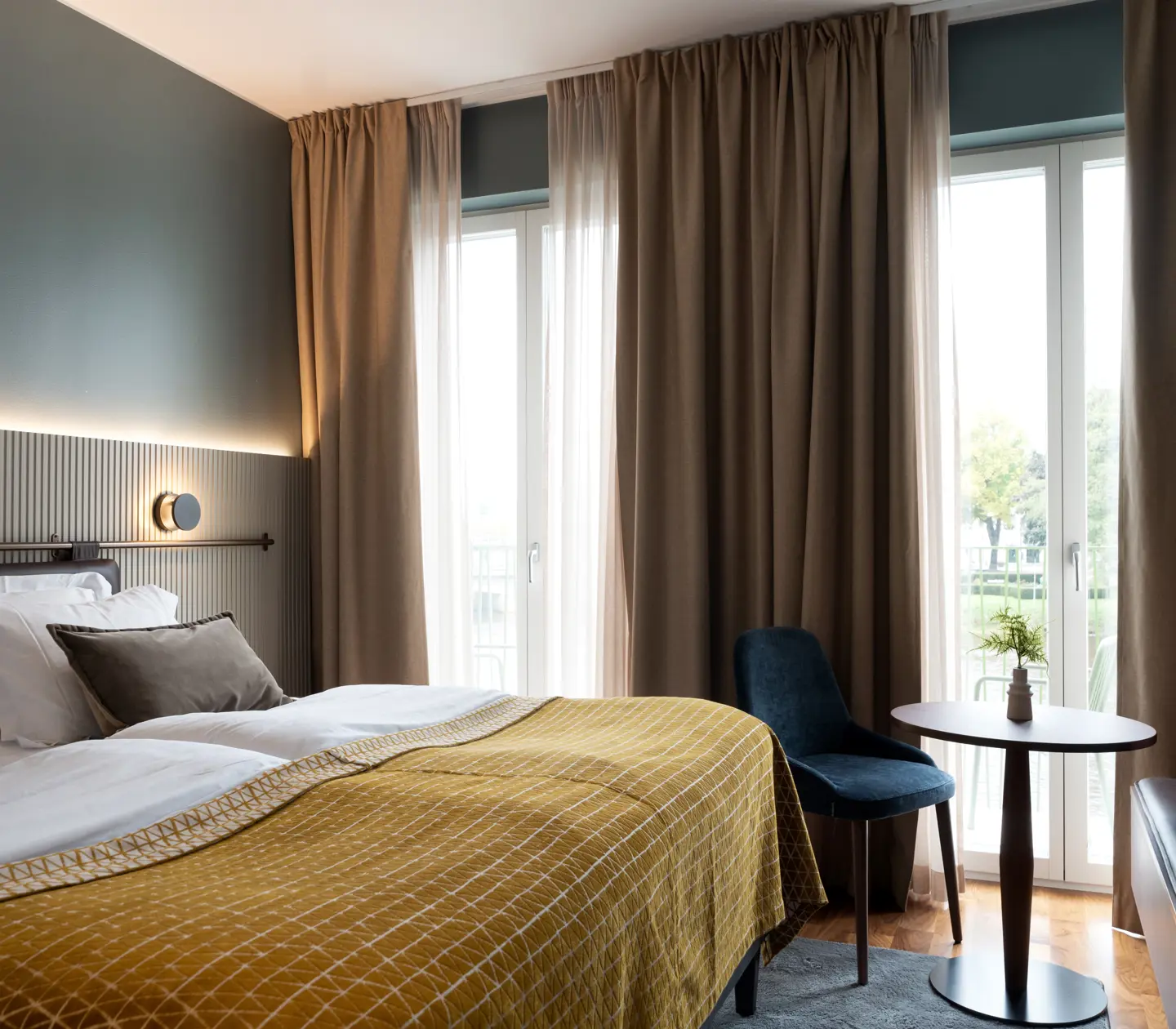 Ombonat hotellrum med dubbelsäng, varma textiler och stora fönster