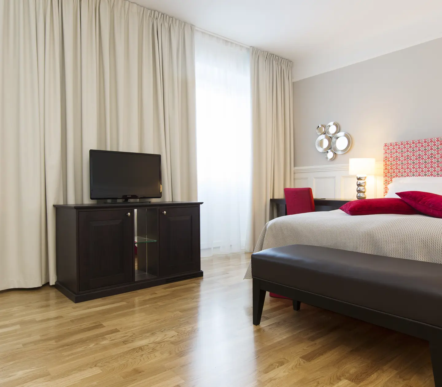 Ljust hotellrum med säng, skrivbord och stora fönster
