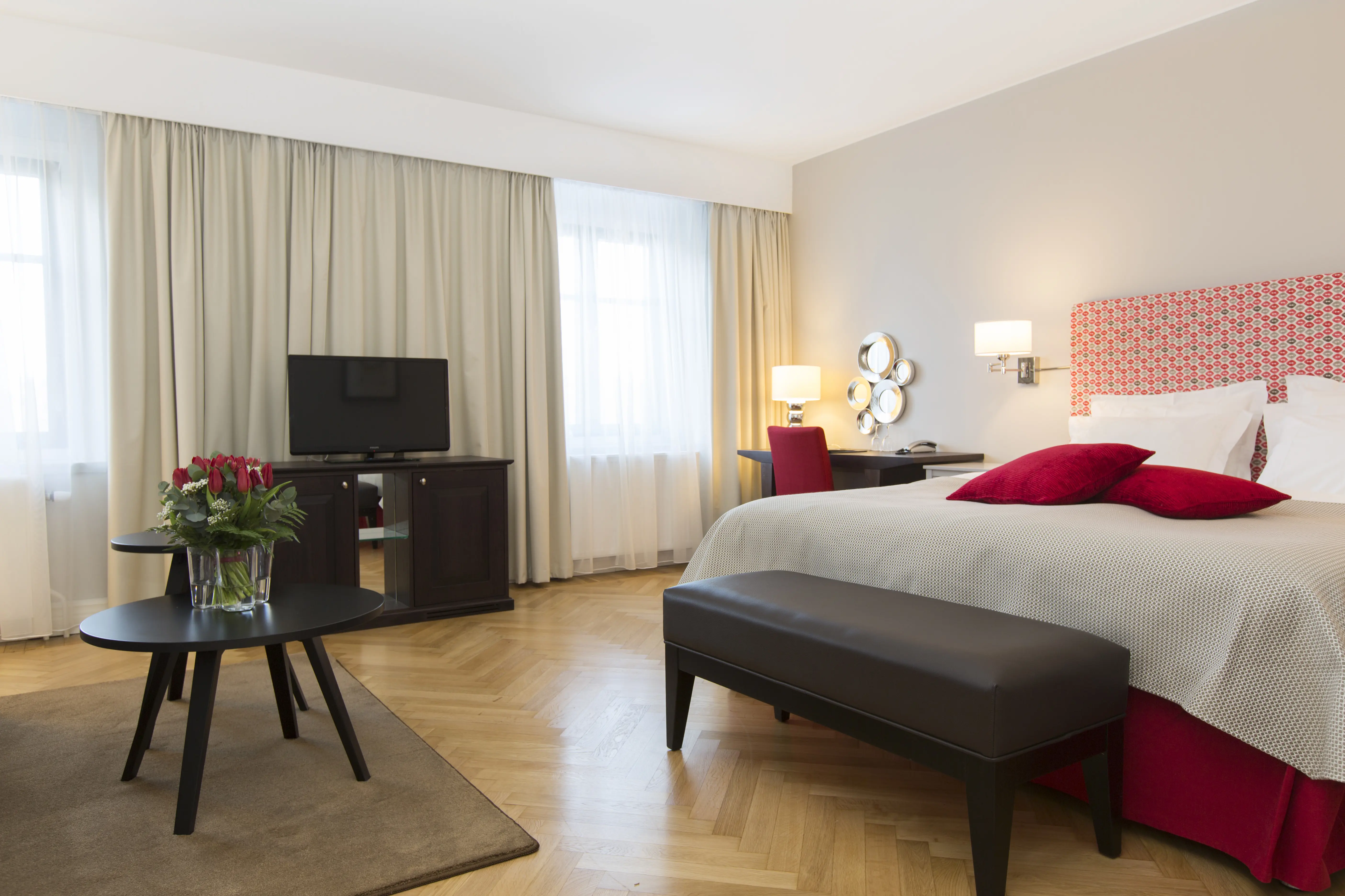 Ljust hotellrum med dubbelsäng, skrivbord och tv