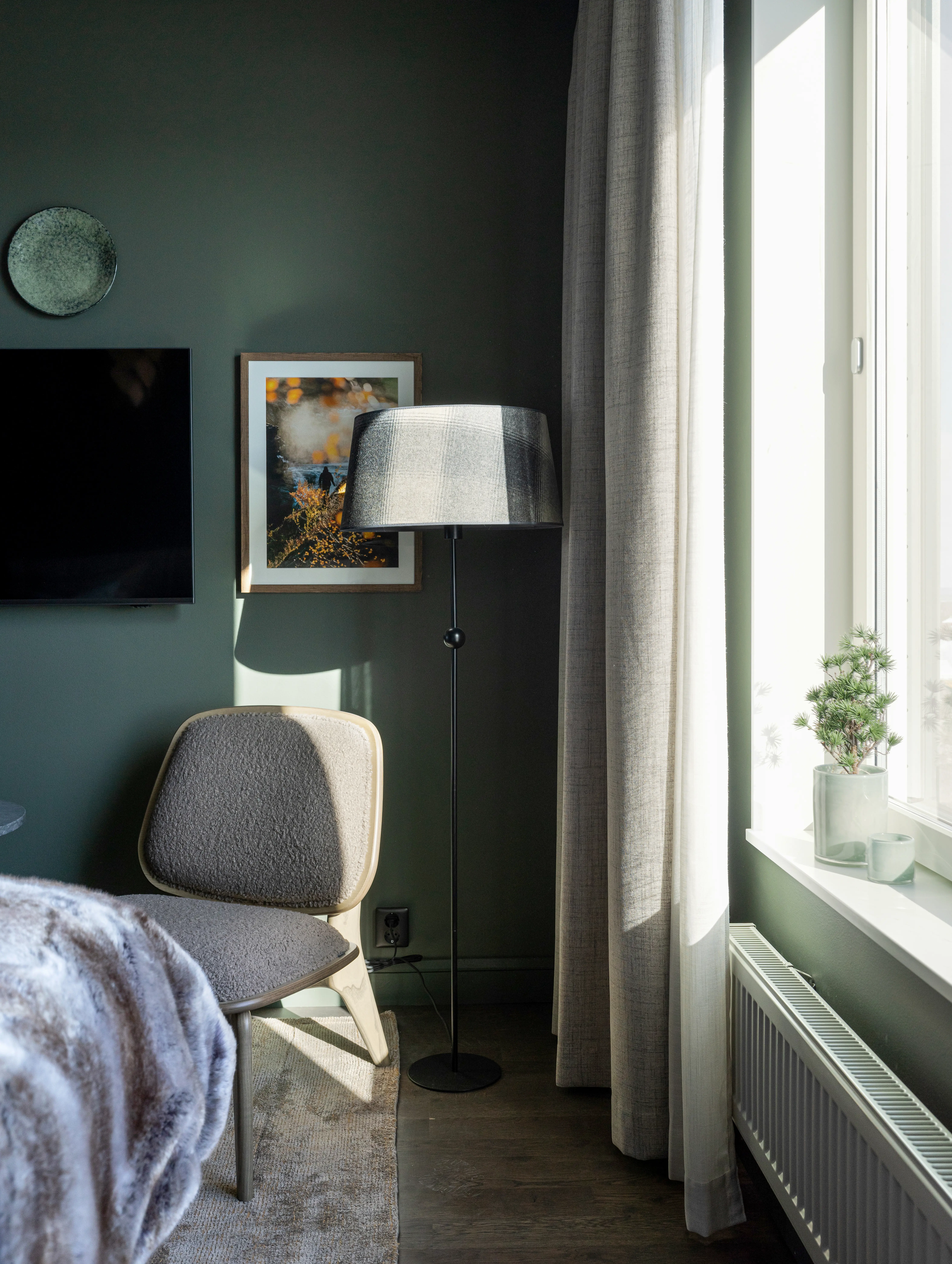 Hotel room with armchair, window, and floor lamp.