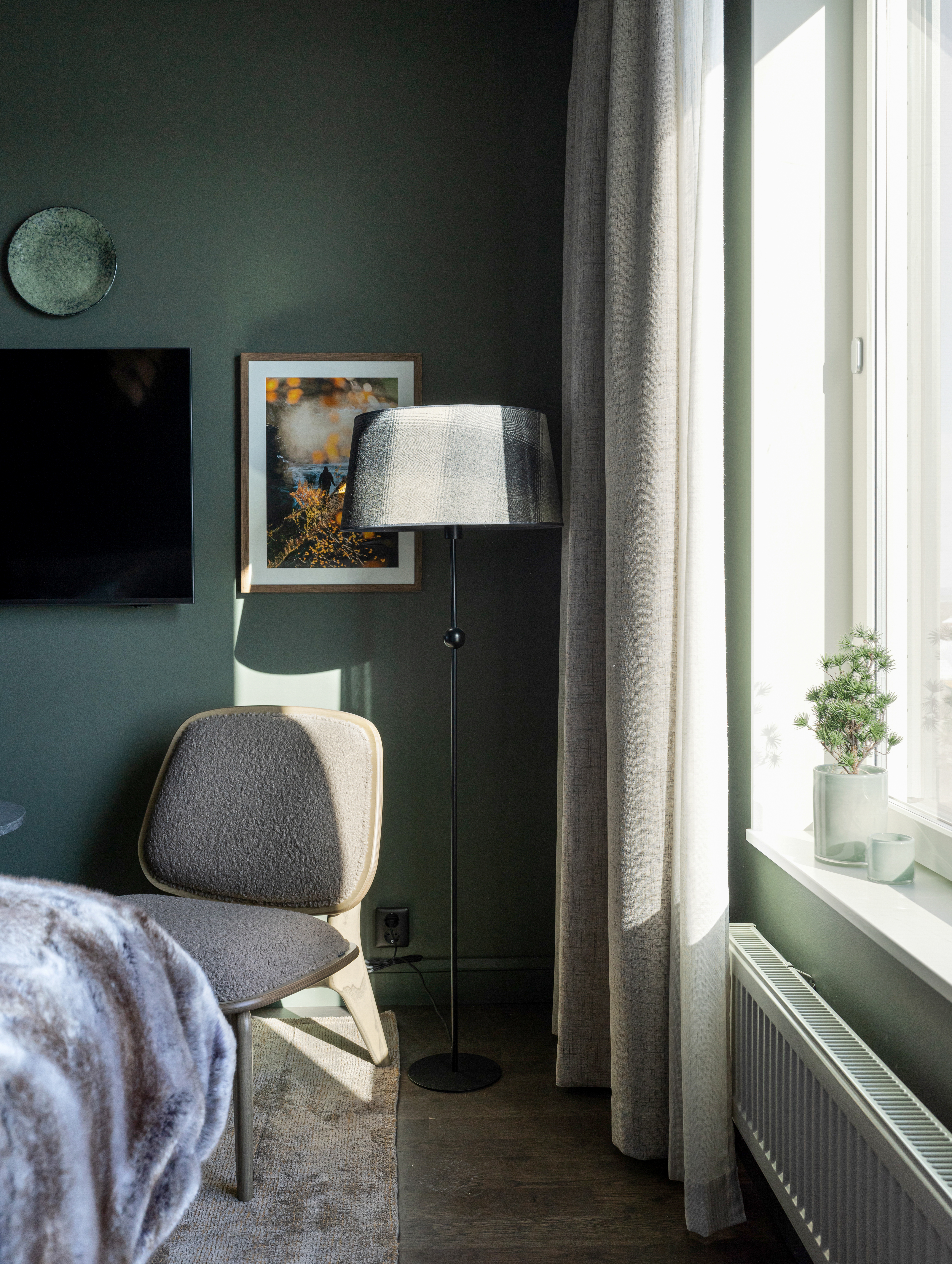 Hotellrum med fåtölj, fönster och golvlampa