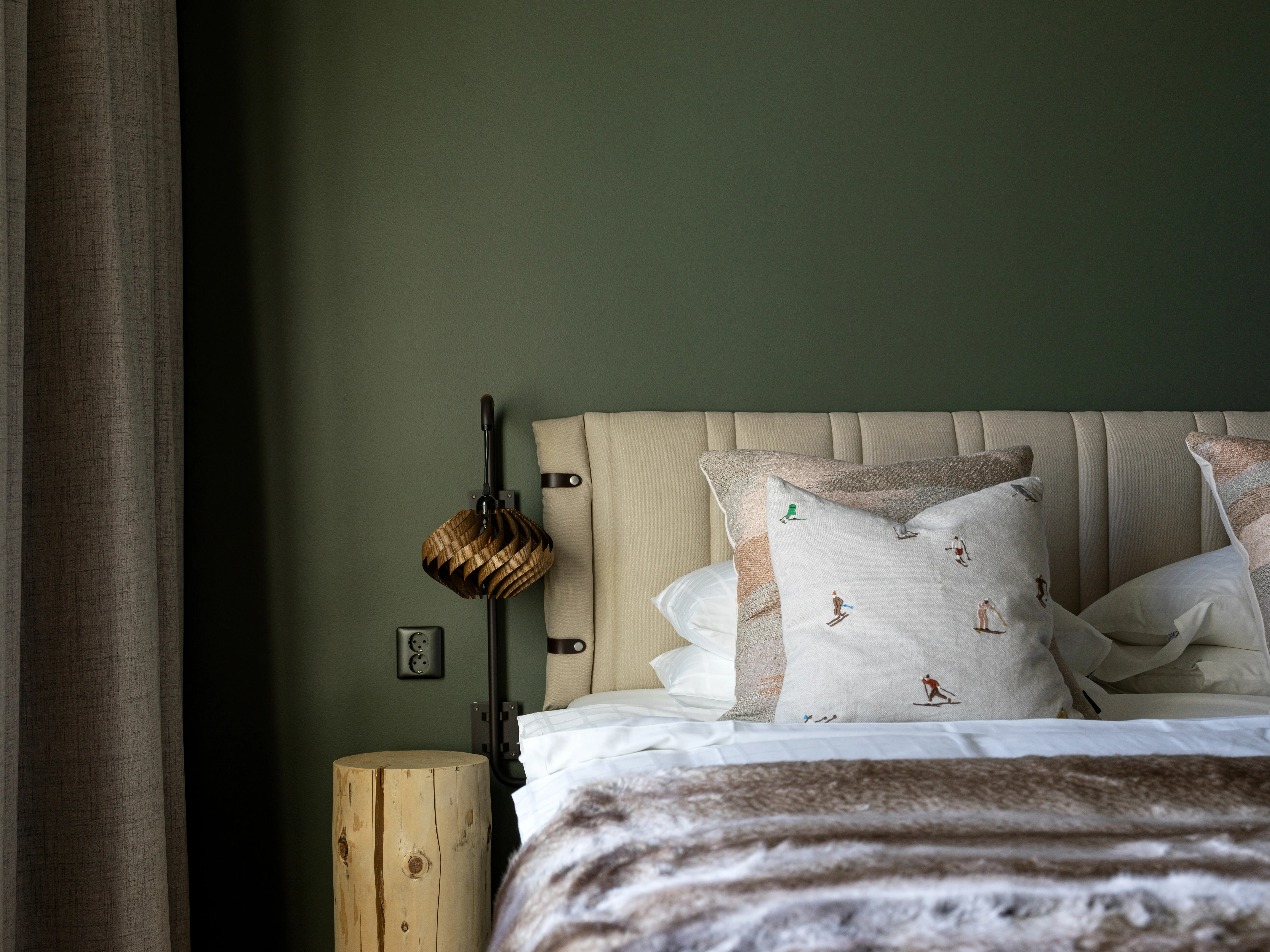 Green hotel room with bed and bedside table