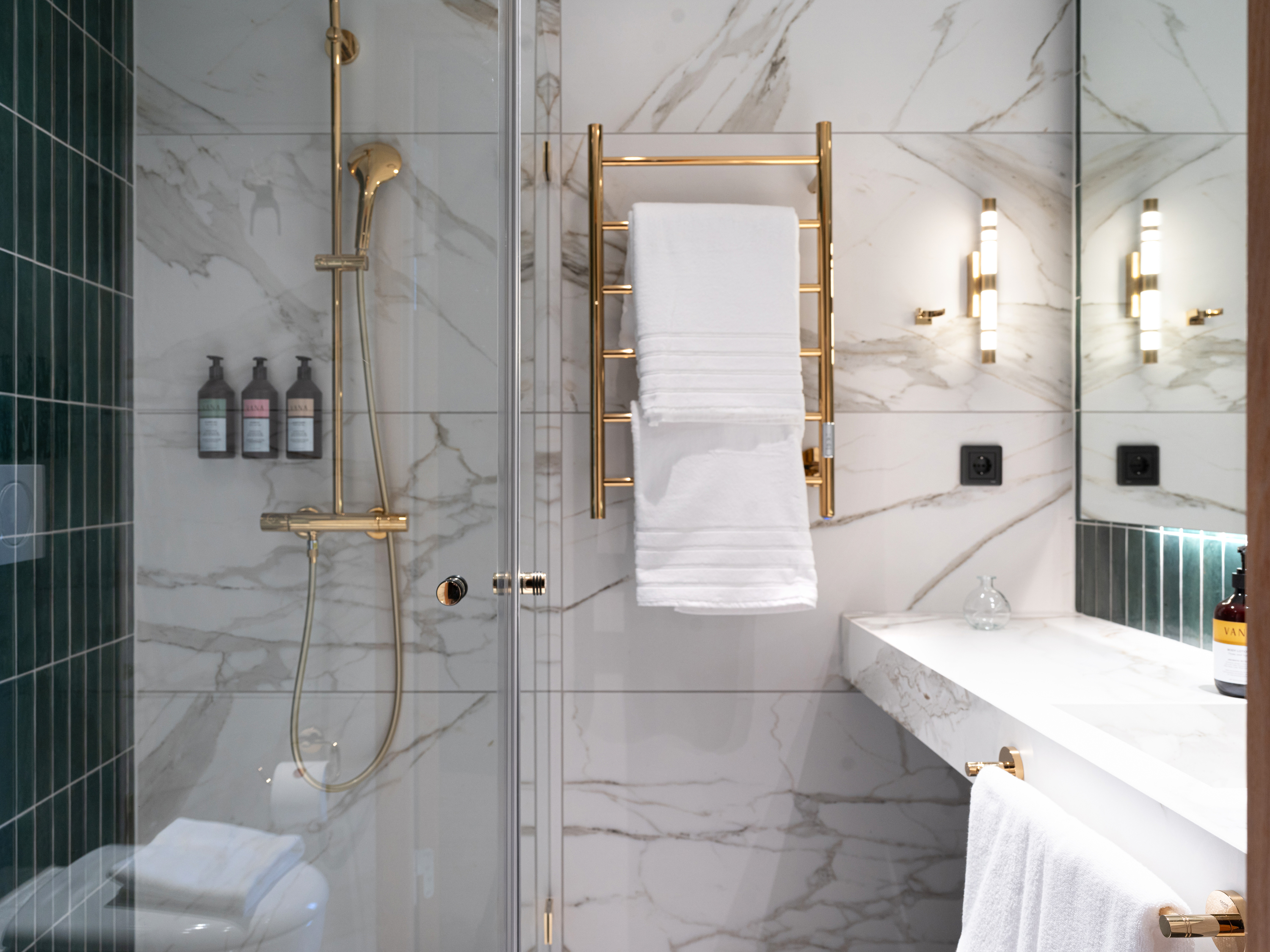 Badrum i grönt kakel med vit marmor och gulddetaljer