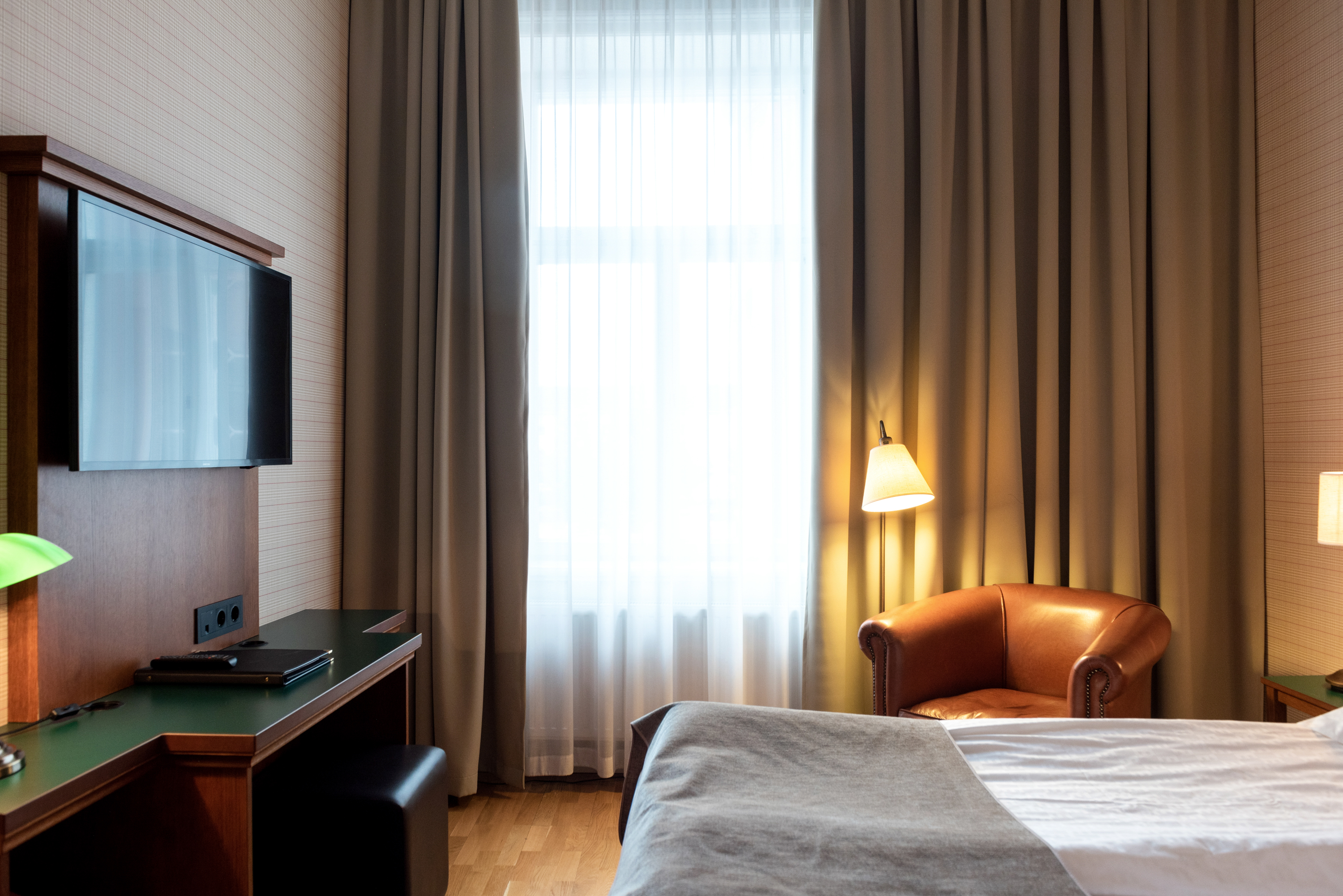 Hotel room with bed, leather armchair and TV