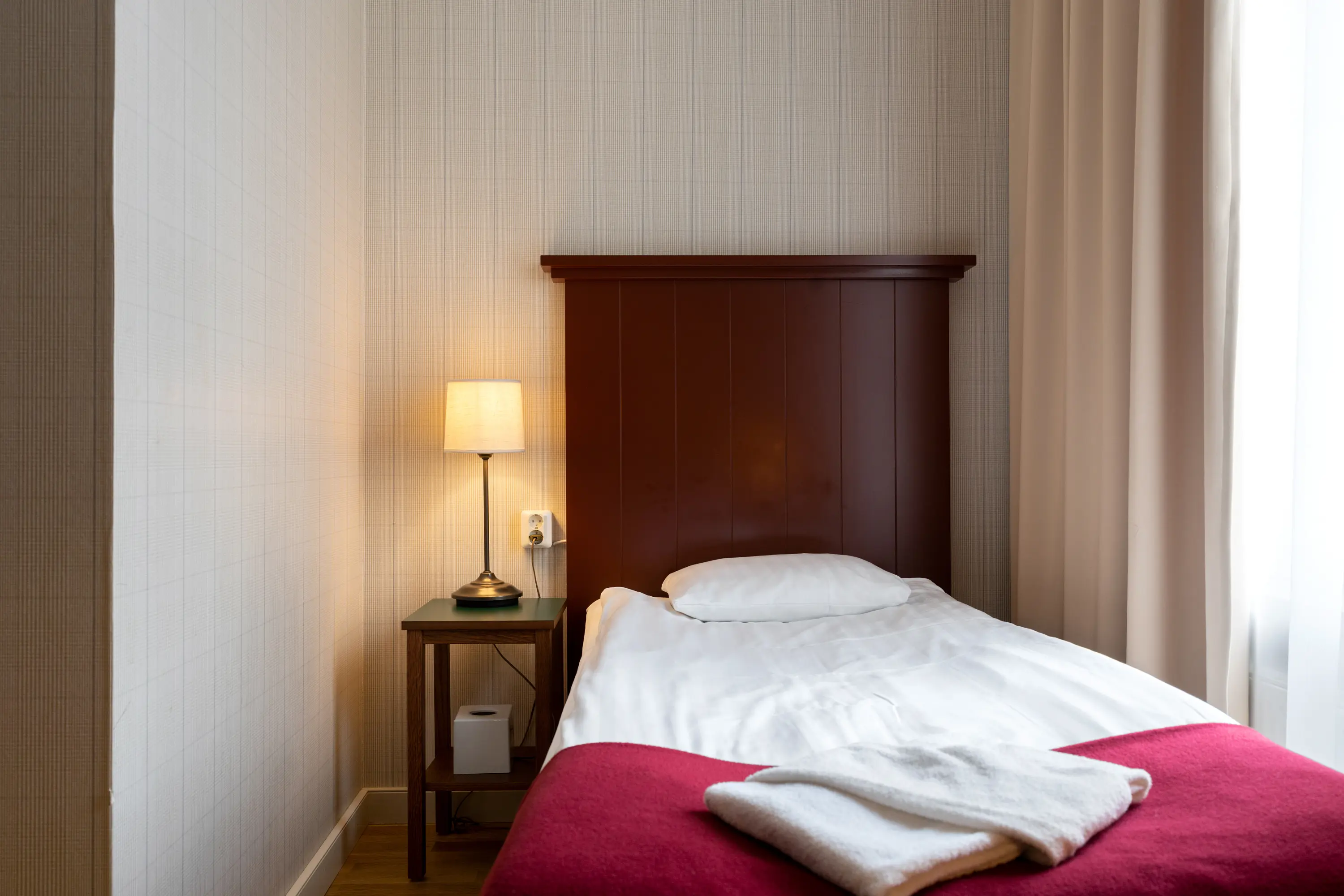Mysigt hotellrum med säng, sänggavel i trä och sänglampa