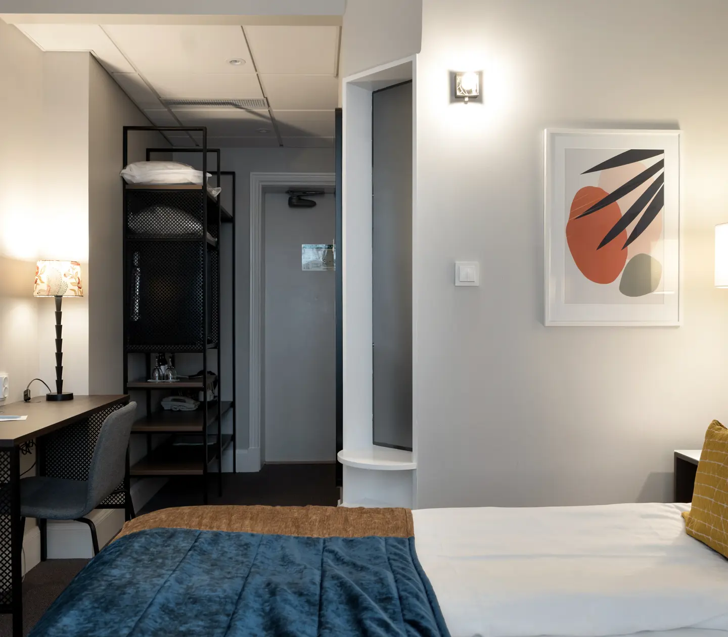Hotellrum med dubbelsäng, skrivbord och tavla