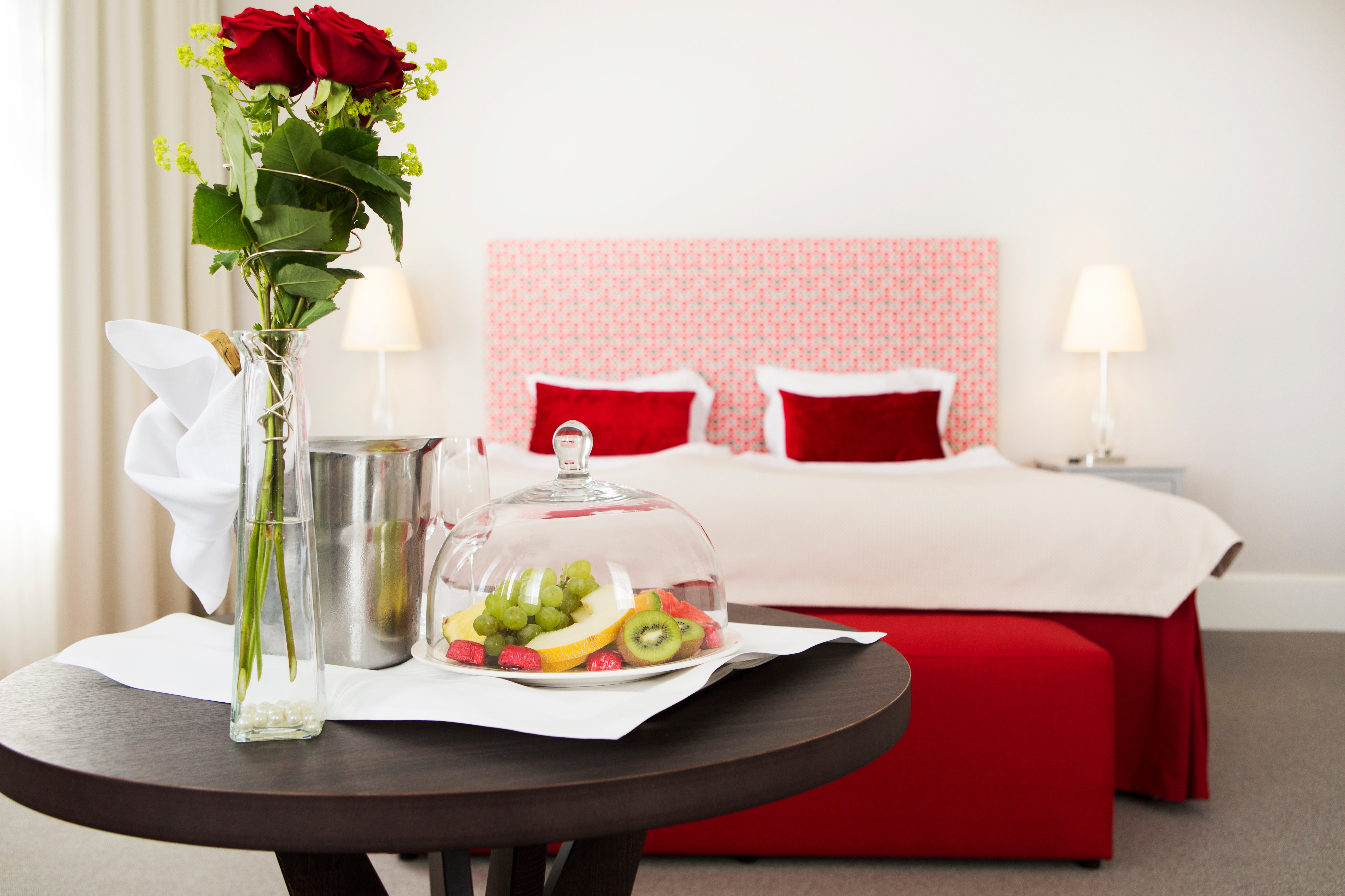 Bright suite with double bed, red textiles and vip on table in front