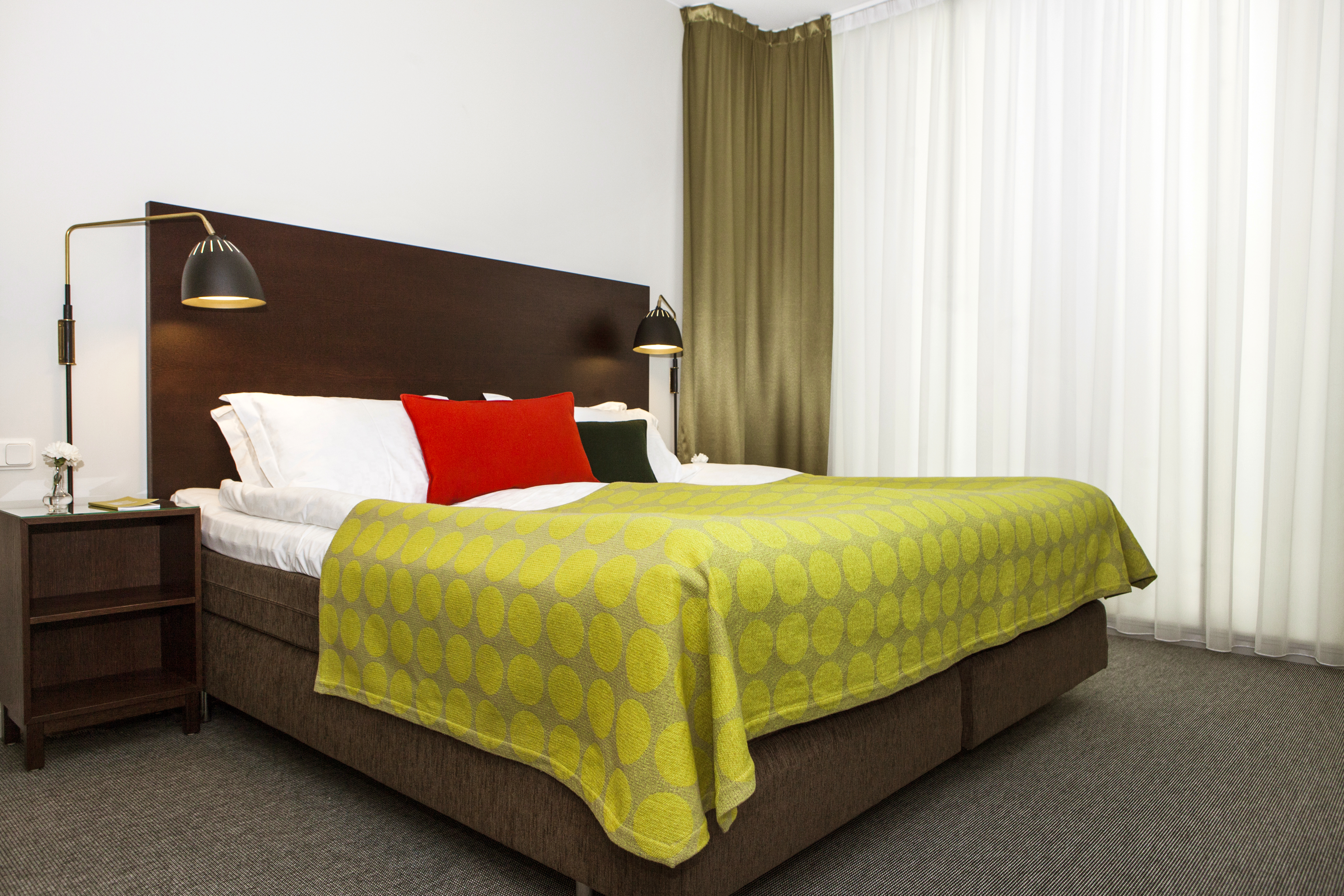 Hotel room with bed, large headboard and bedside lamps