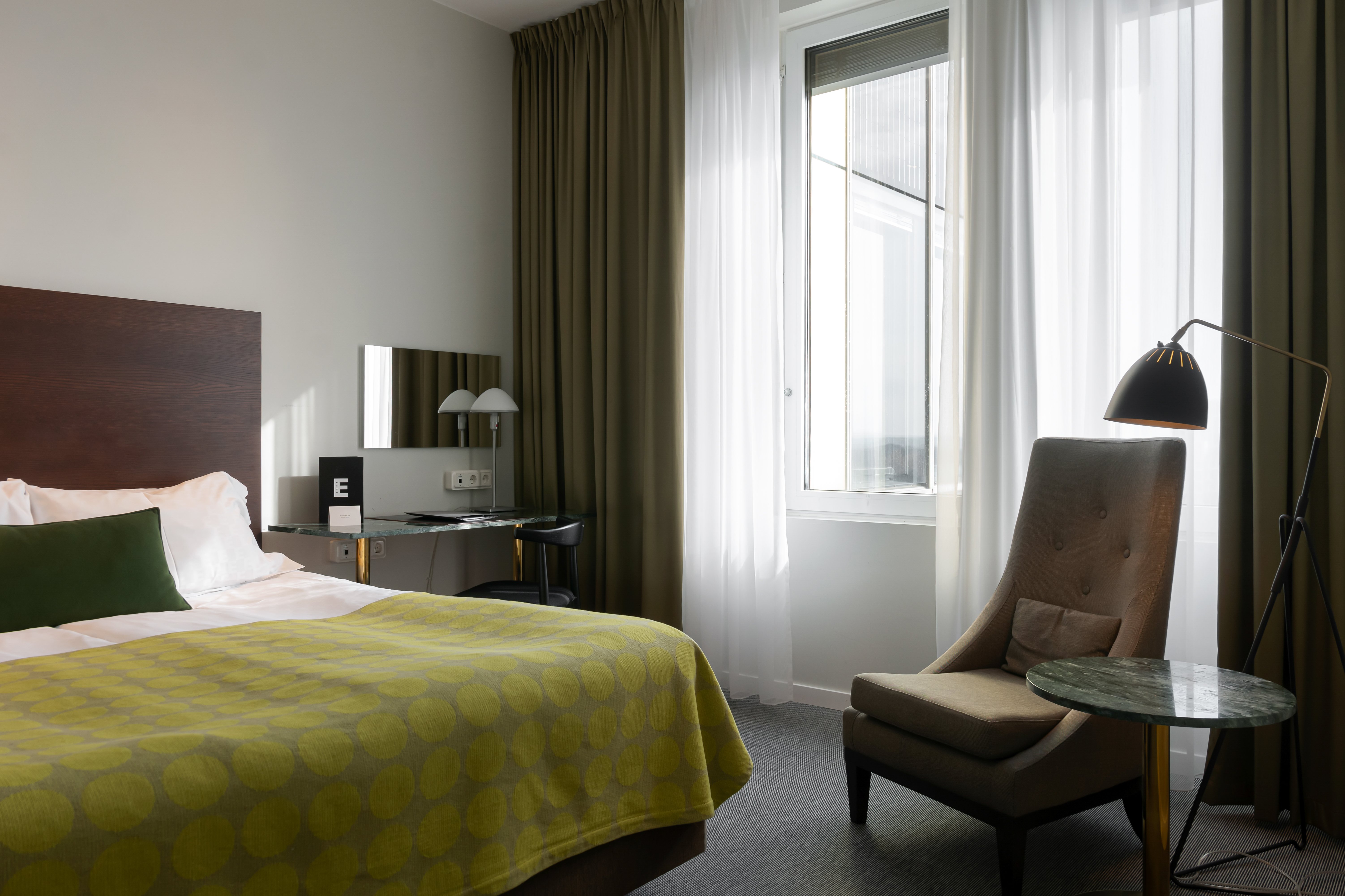 Bright hotel room with bed, armchair and balcony door