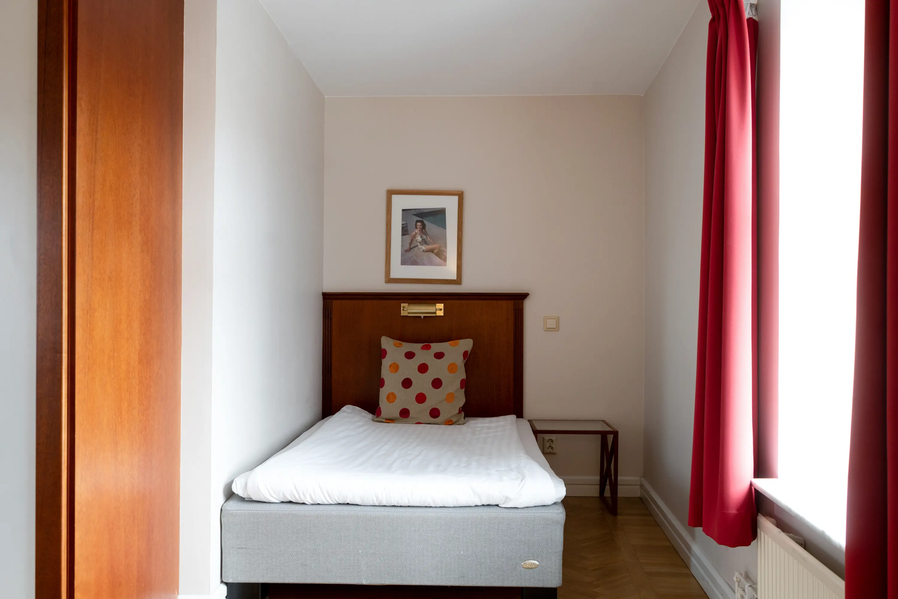 Hotellrum med säng, sänggavel i trä och fönster