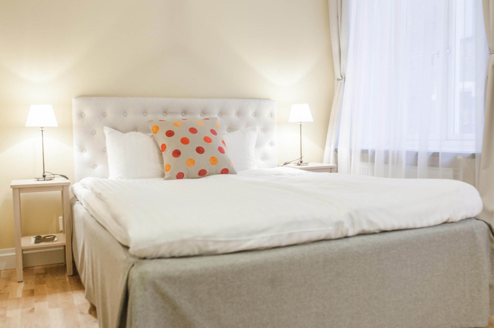 Hotel room with bed, white headboard and polka dot pillows
