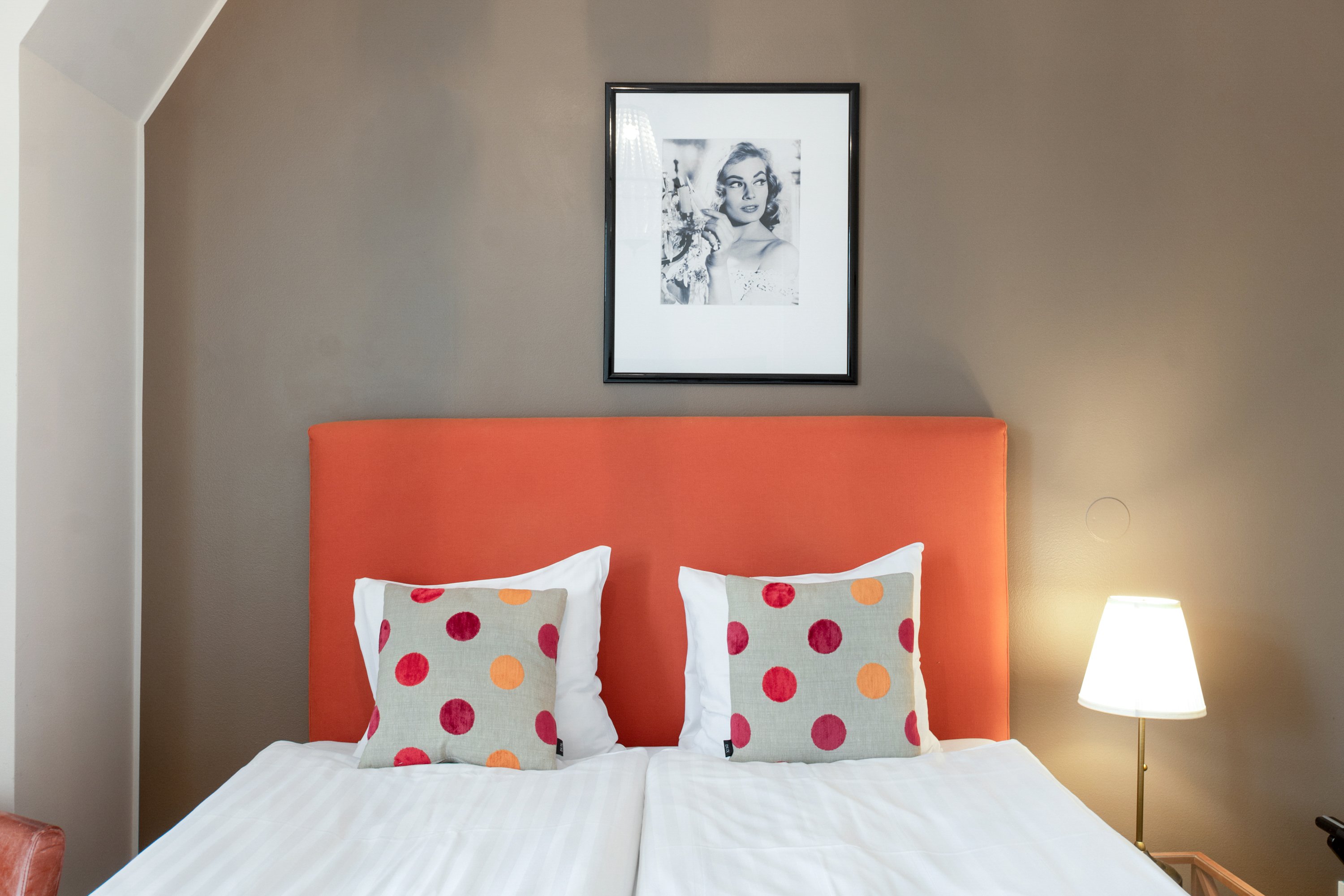 Hotel room with bed, orange headboard and polka dot pillows