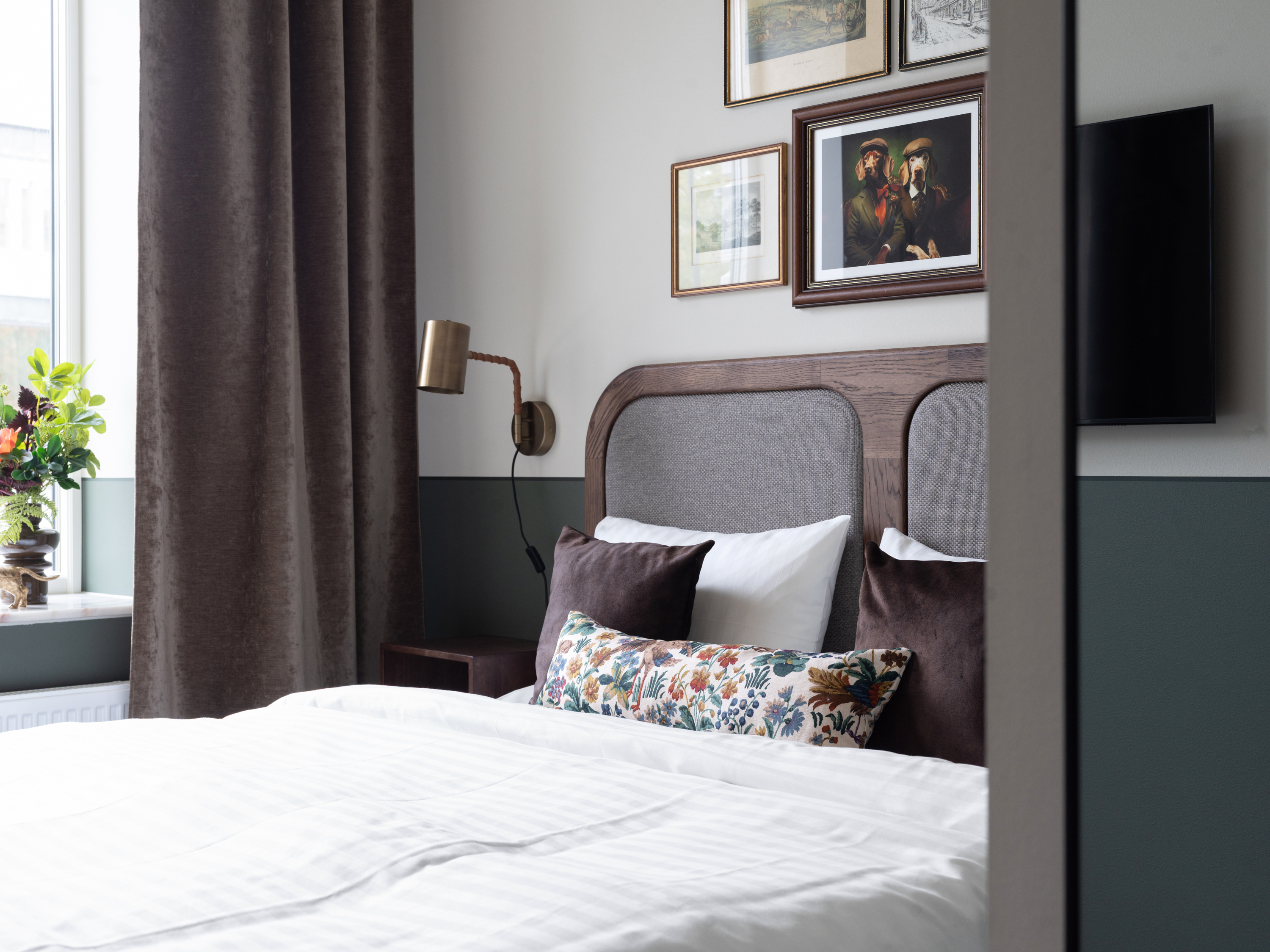 Ljust hotellrum med säng, skrivbord och tavla