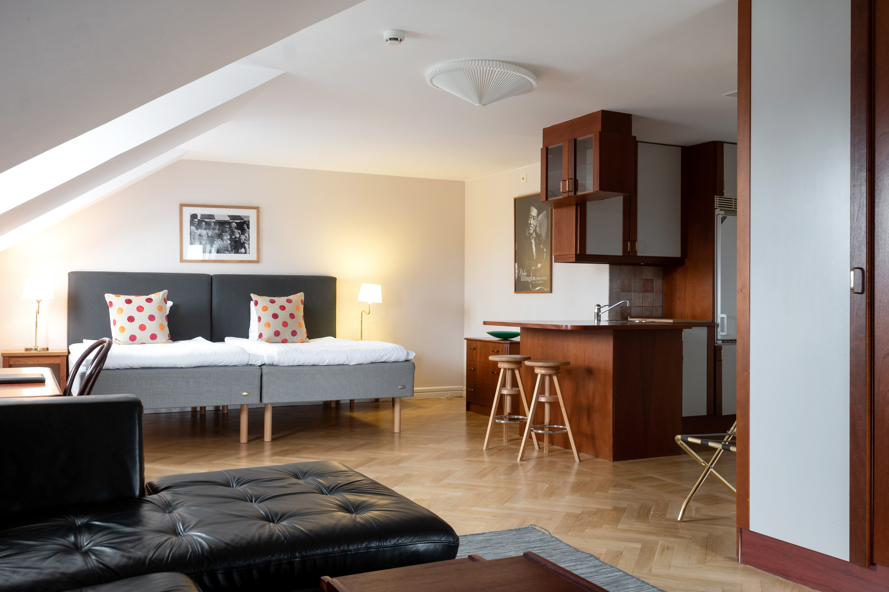 Hotel room with beds, black sofa and kitchen